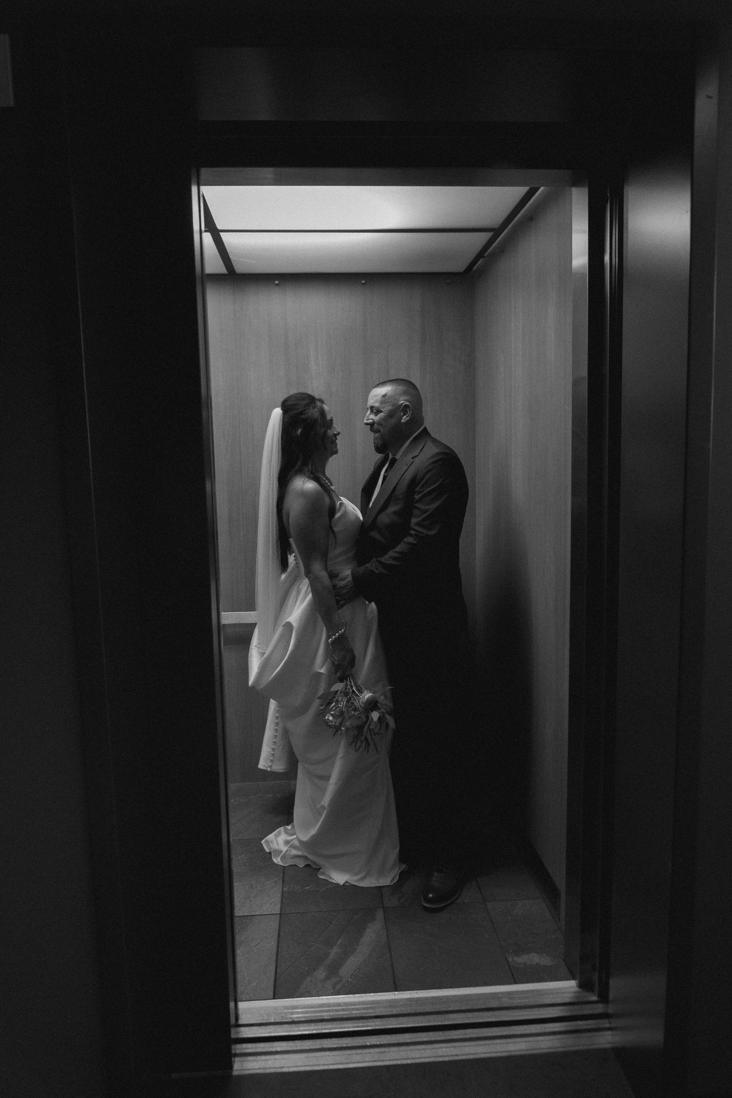 A couple shares a romantic moment in an elevator on their wedding day.