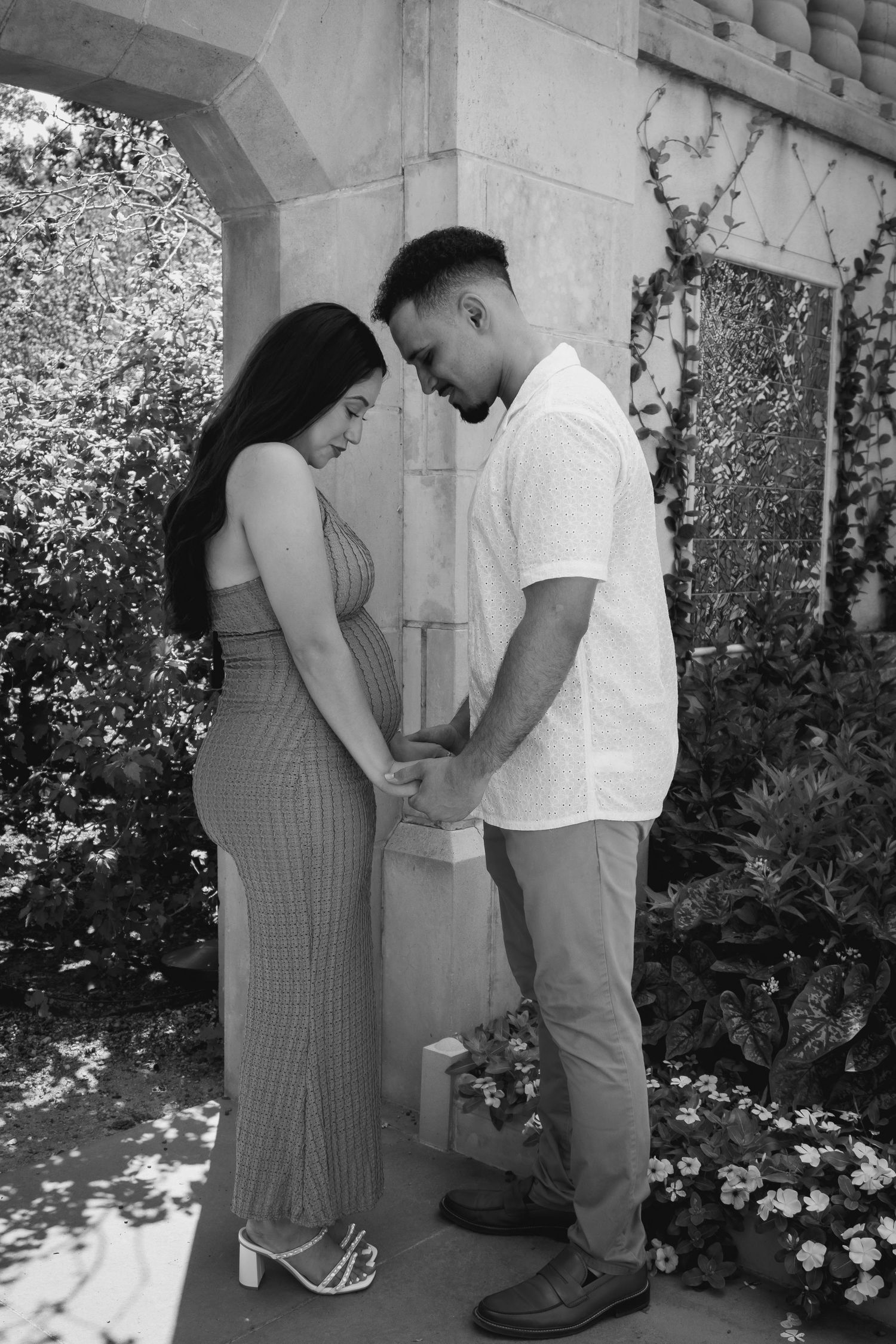 A couple in a garden setting share a tender moment in a series of black and white photos.