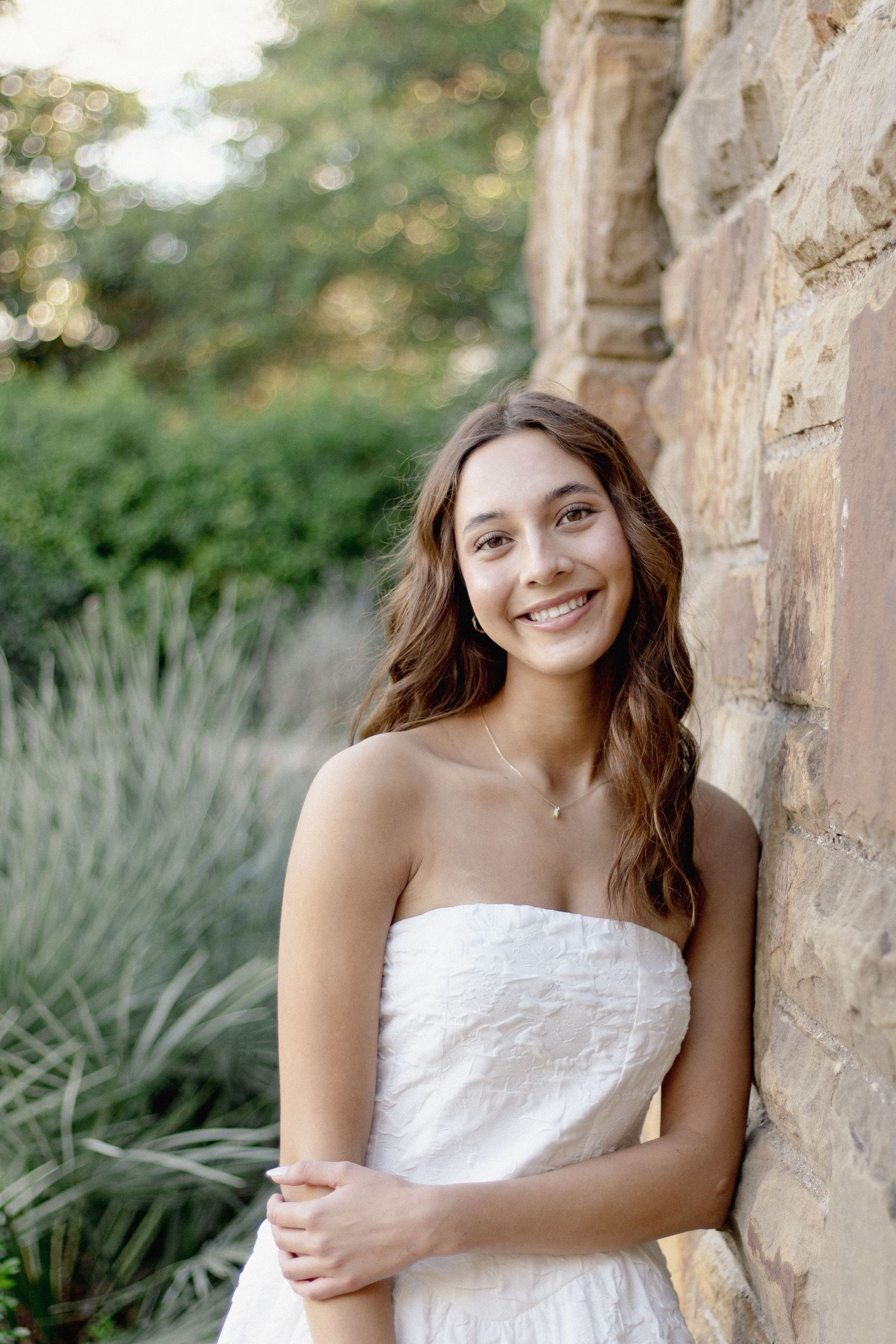 Portrait against a stone wall with decorative plants in the background.