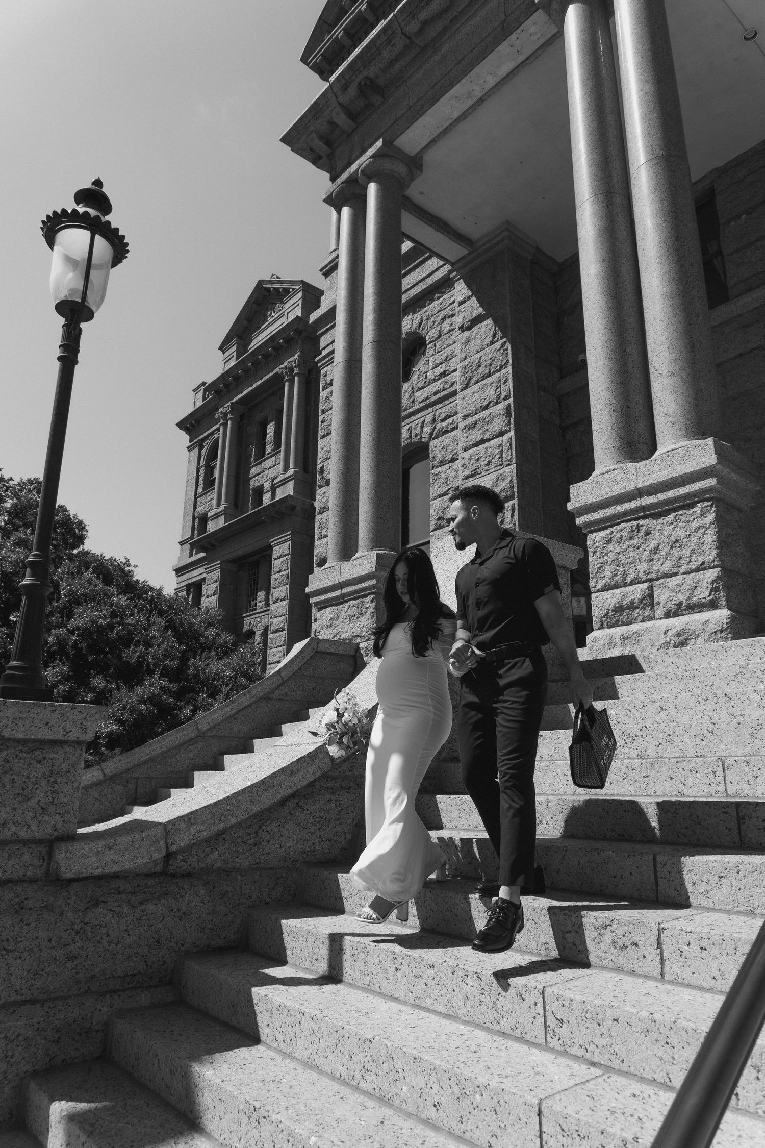 A sequence of black and white photos showing a couple sitting and posing on stone steps in front of white columns.