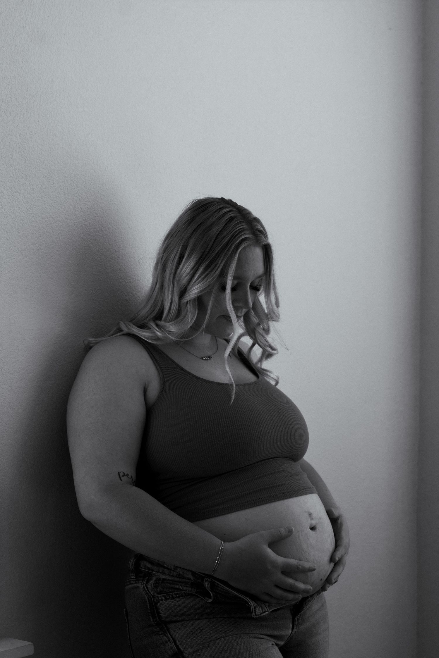 A black and white maternity photo showing an expectant mother cradling her belly.