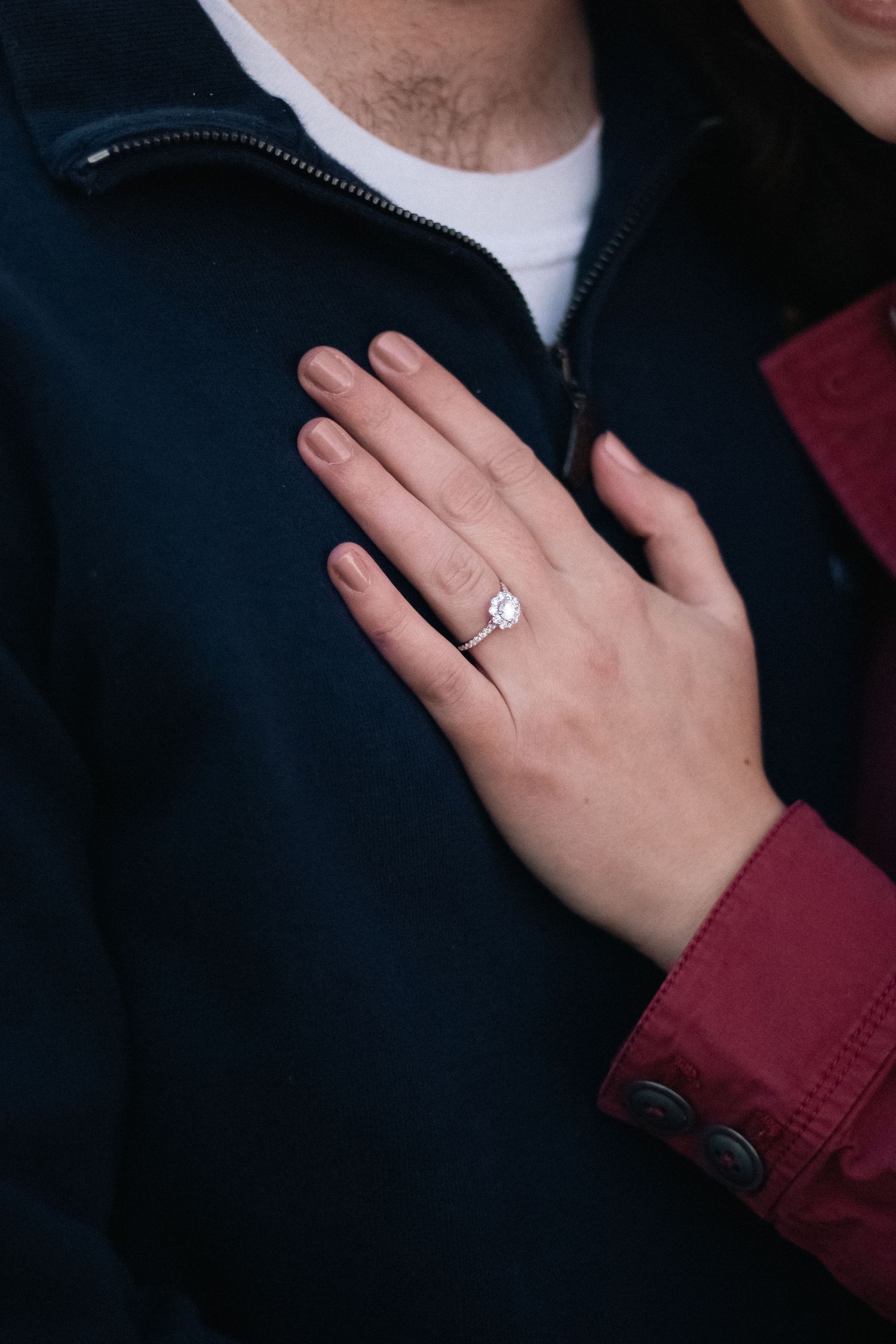 Detailed shots of engagement ring on hand against dark clothing.