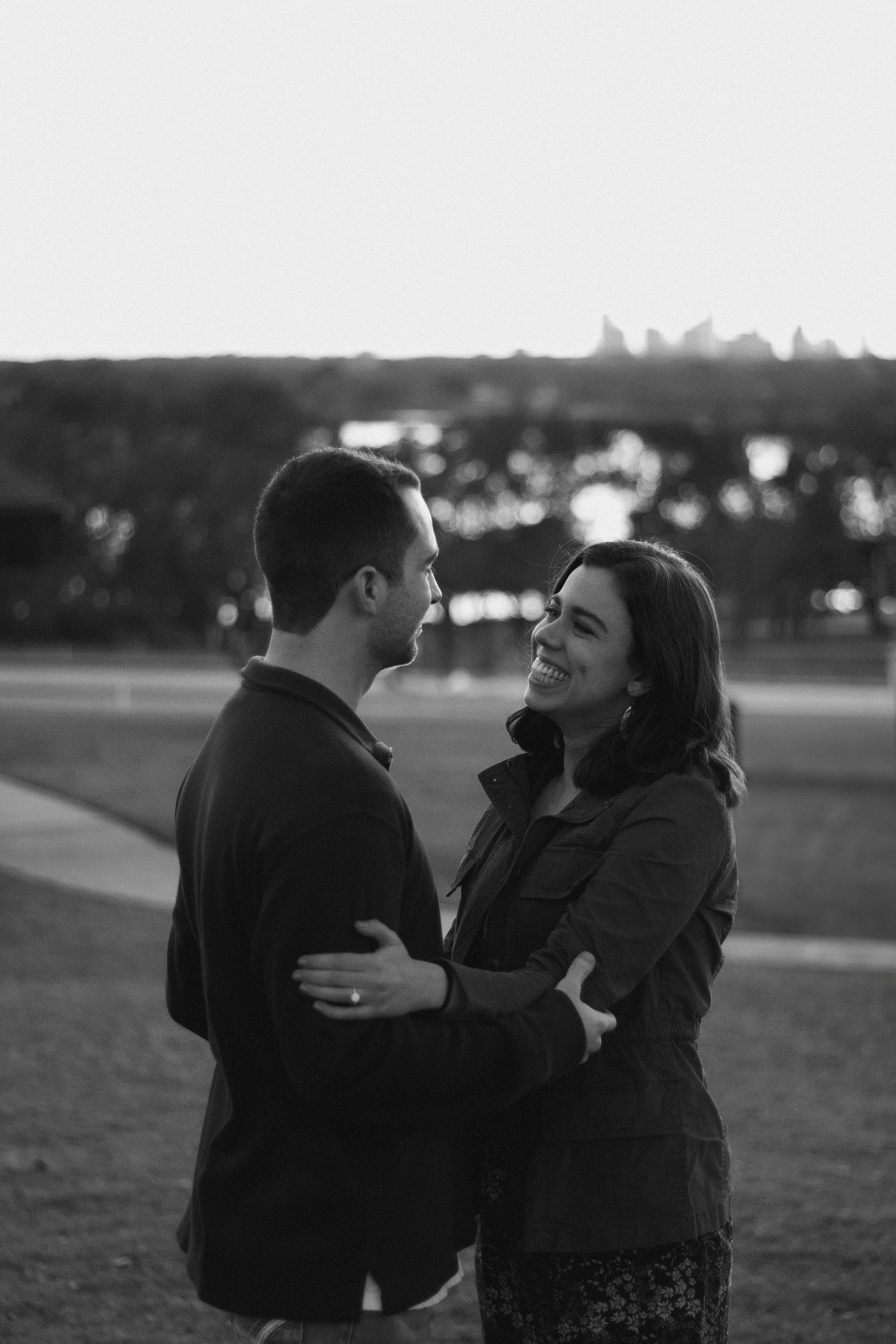 Black and white series of a couple embracing in an open field at dusk.