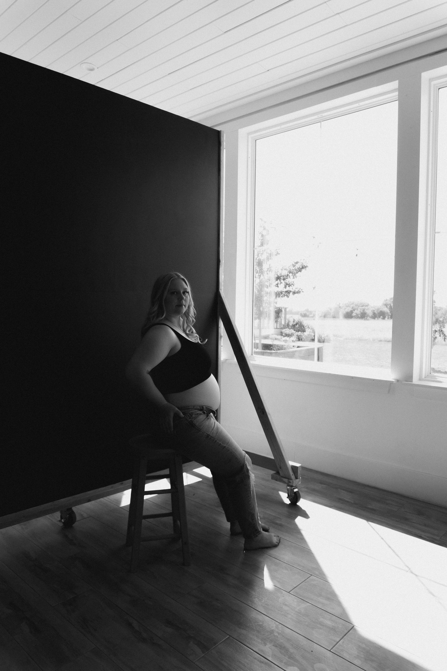 Figure sitting in dramatic window light on wooden floor creating artistic silhouettes.