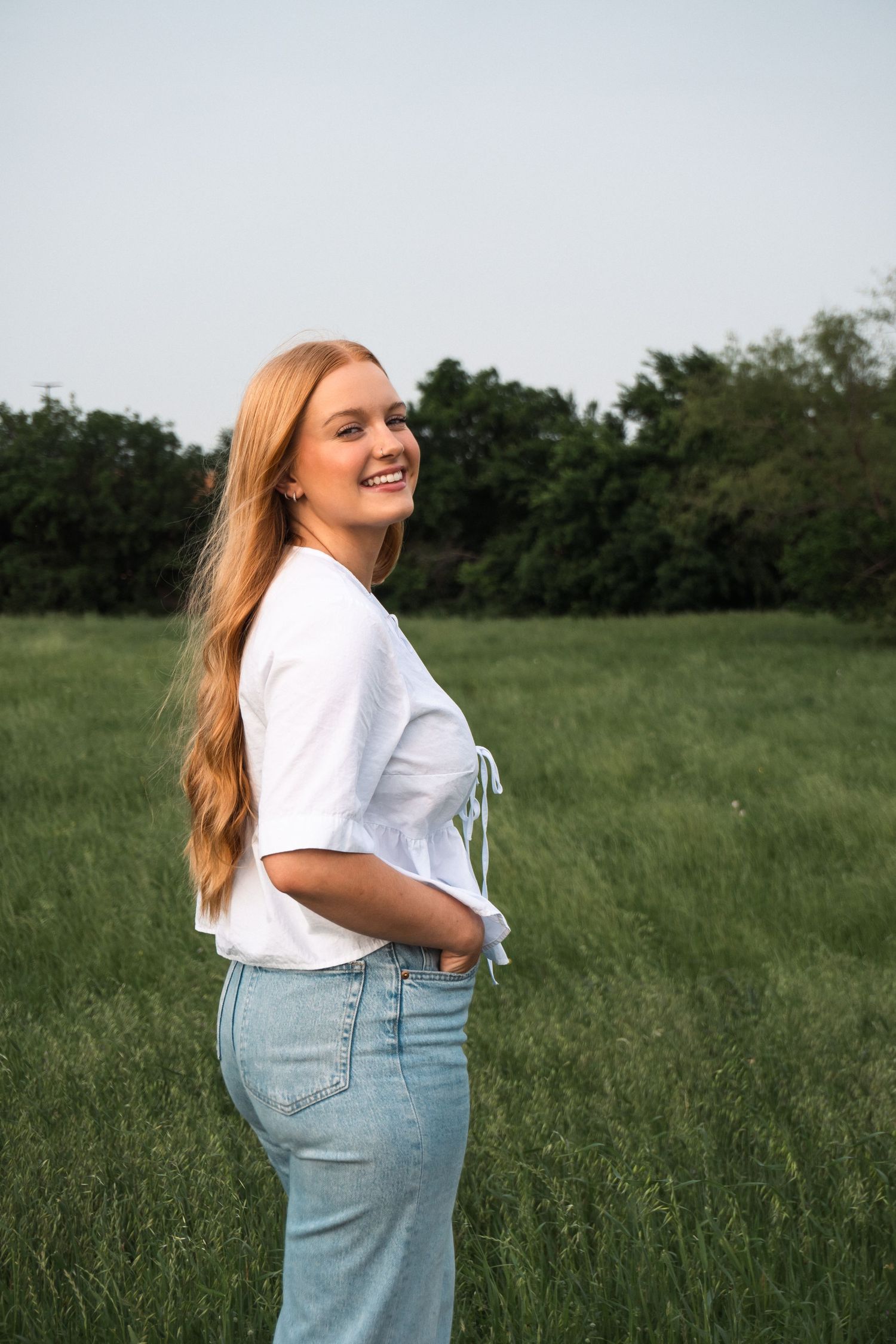 Person in casual attire enjoying a sunny day in an open meadow.
