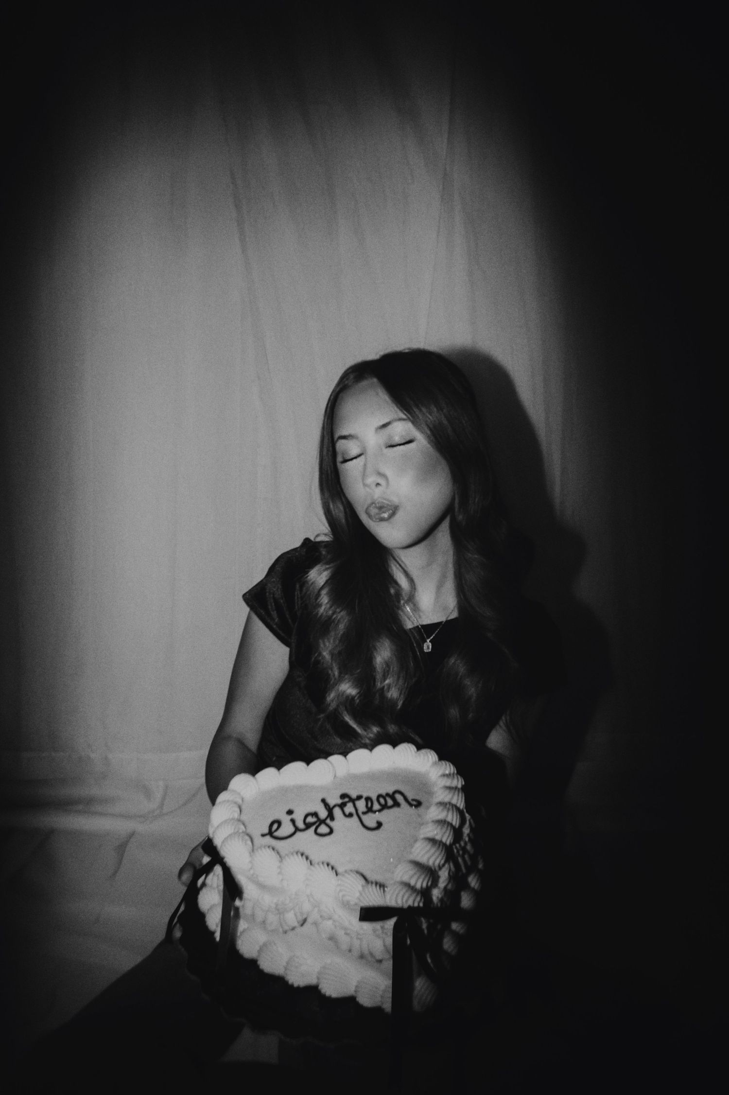 A series of black and white photographs showing someone blowing out birthday candles on a cake in moody lighting.