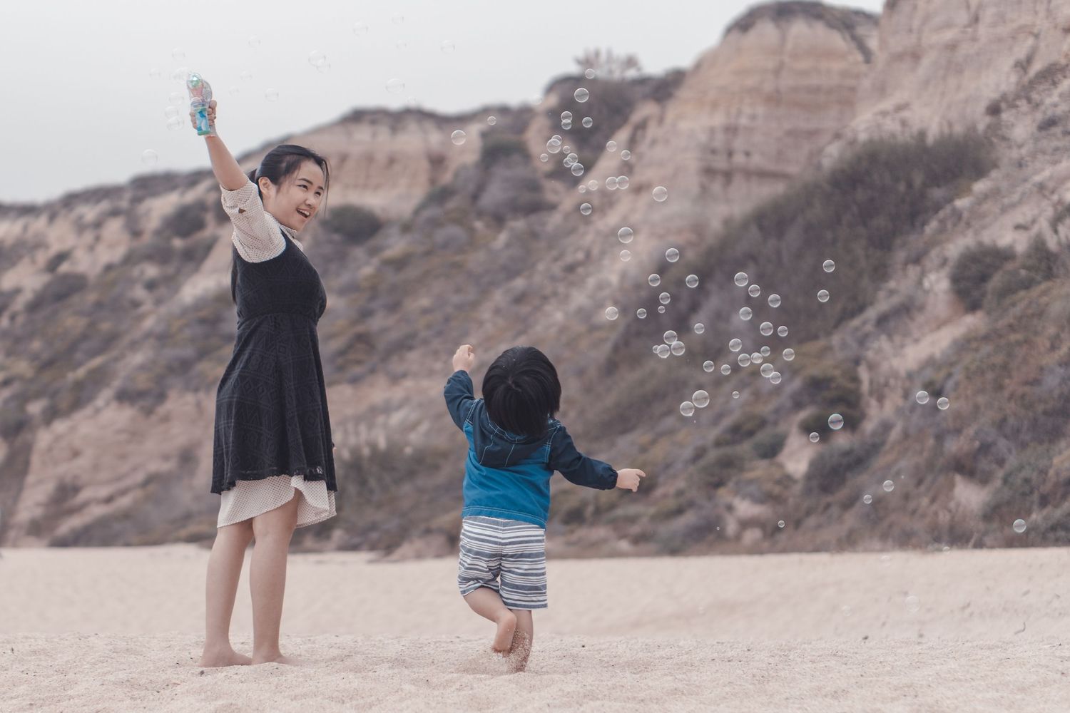 Lifestyle photo of mother and toddler son playing with bubbles