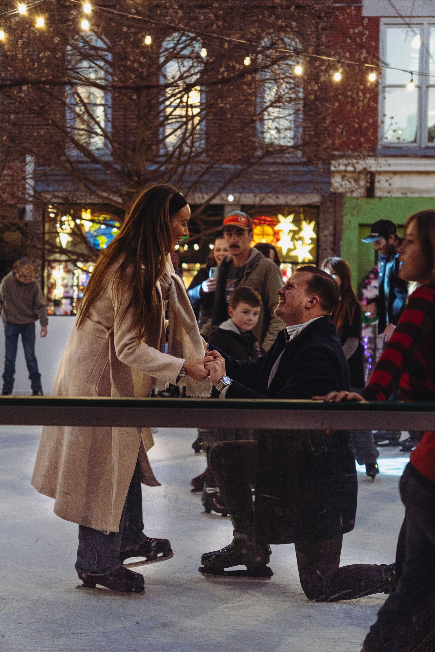 Man proposes on ice skating rink while onlookers watch the romantic moment.