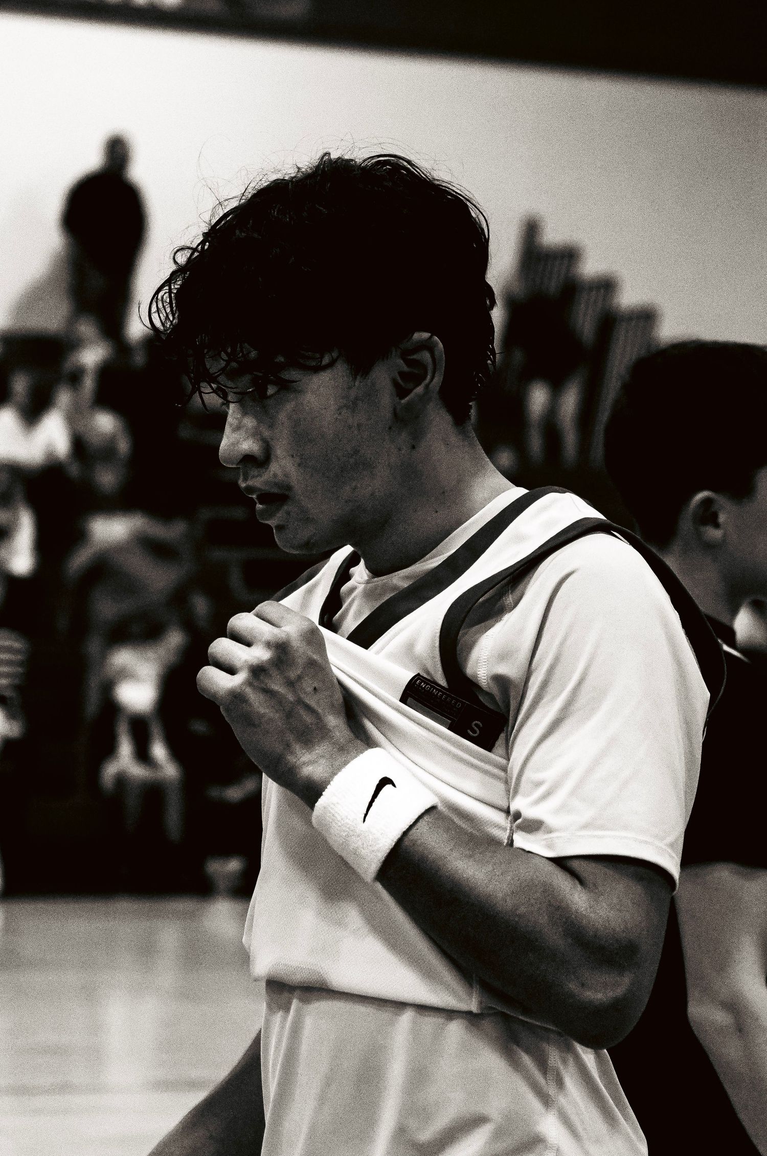 Black and white close-up of a young male basketball player in a white Nike jersey during a game.
