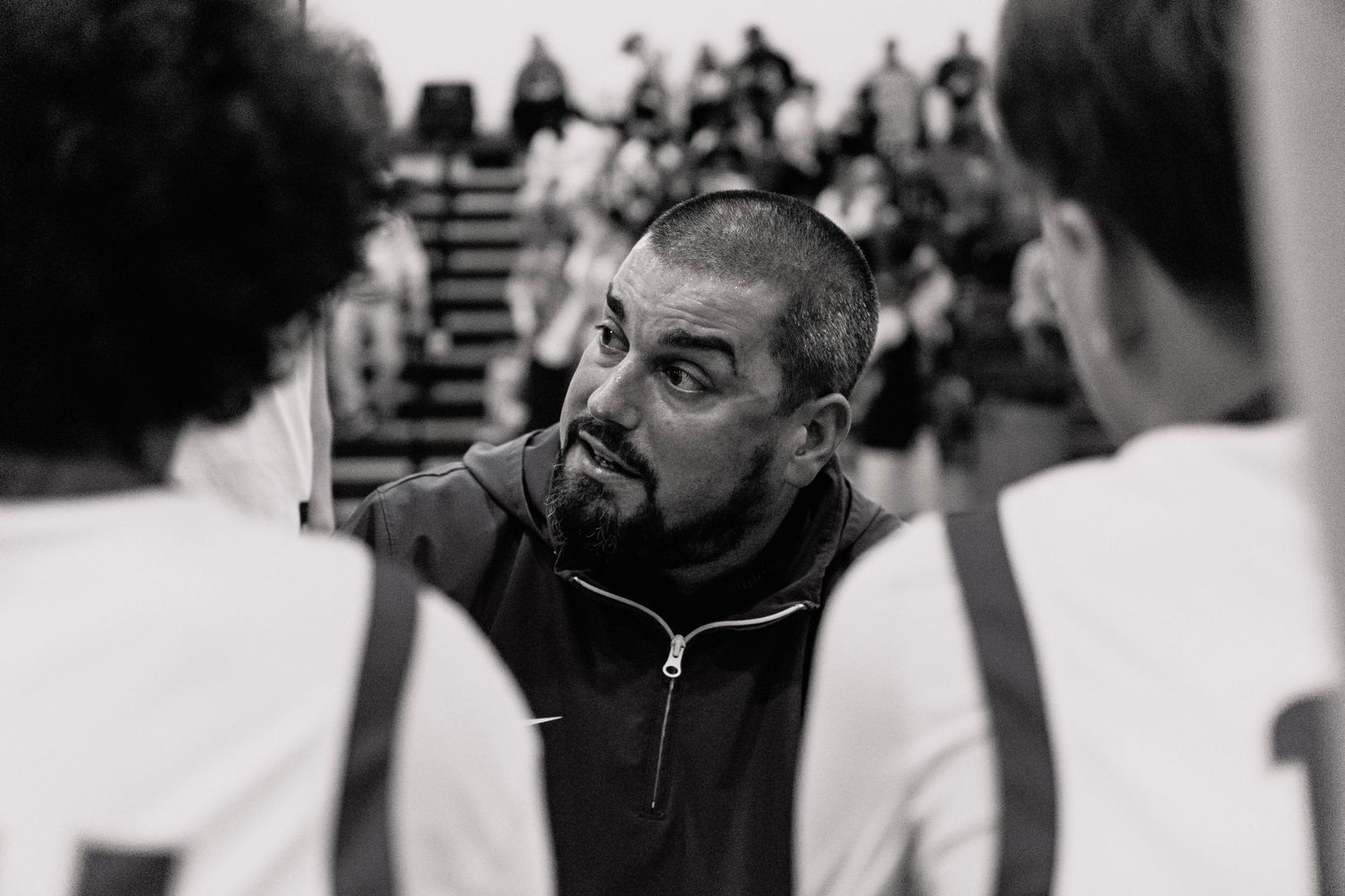 Black and white photo of a basketball coach giving an intense pep talk to players during a timeout.