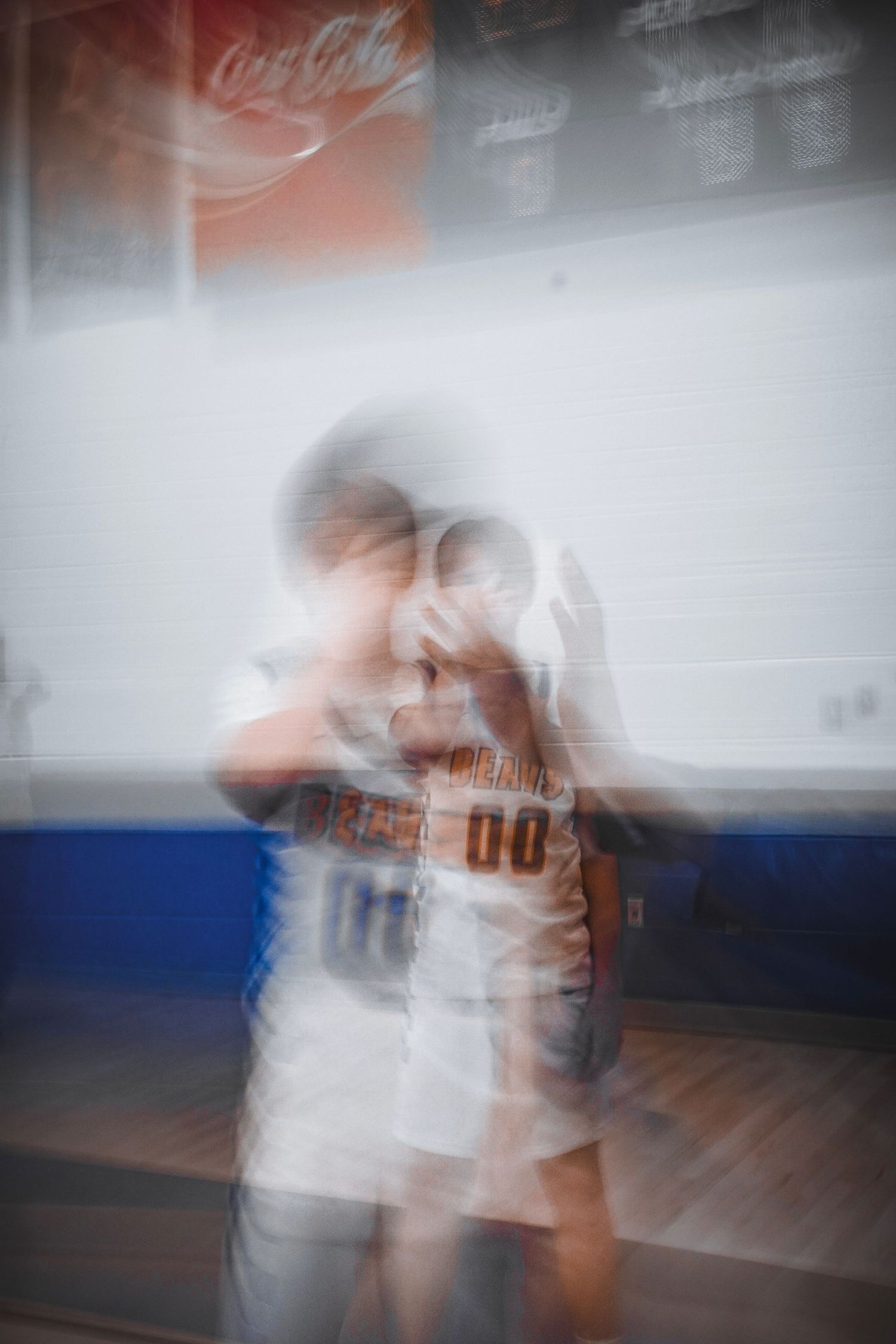 Two basketball players embrace on an indoor court captured with motion blur effect.