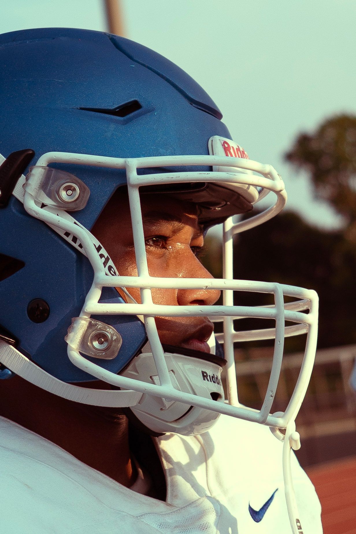 Close-up of football player wearing blue Riddell helmet with white face mask.