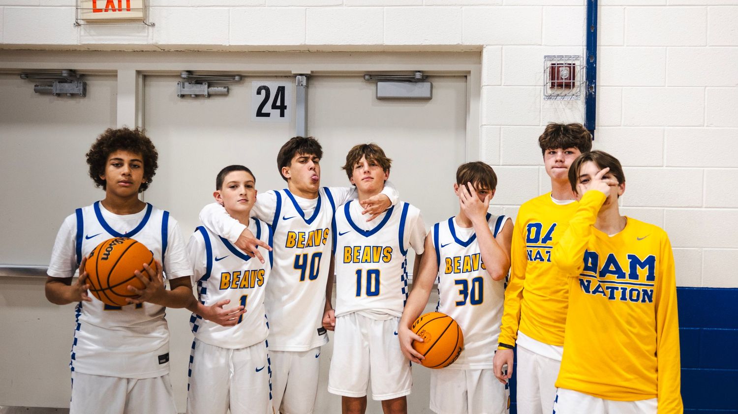Youth basketball team in Beaus uniforms lined up against gym wall before a game.