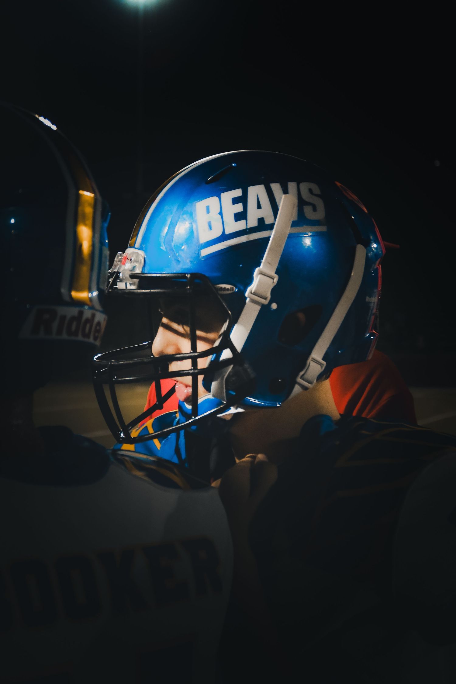 Close-up of a blue Bears football helmet illuminated dramatically in dark stadium lighting.
