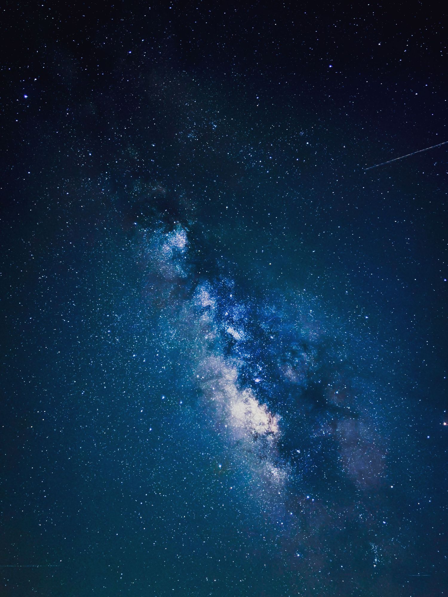 Breathtaking Milky Way galaxy stretching diagonally across a deep blue starry night sky.