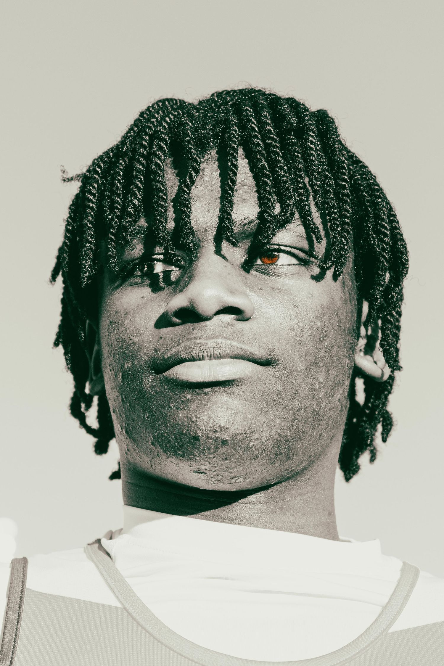 Close-up portrait of a young Black man with twisted dreads looking upward in monochrome.