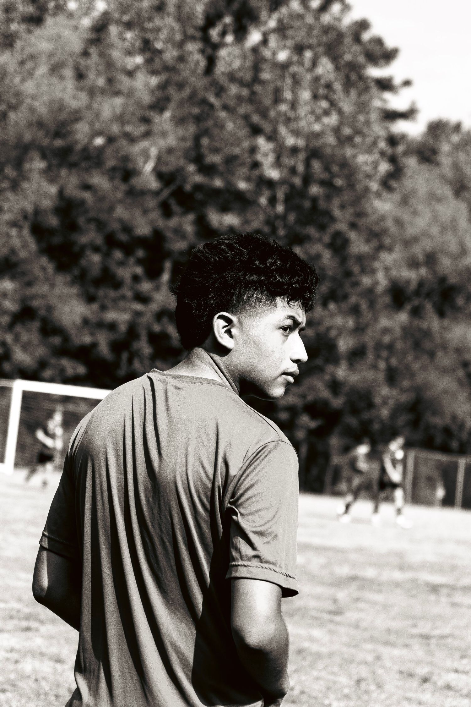 Black and white photo of a soccer player looking over his shoulder on an outdoor field.
