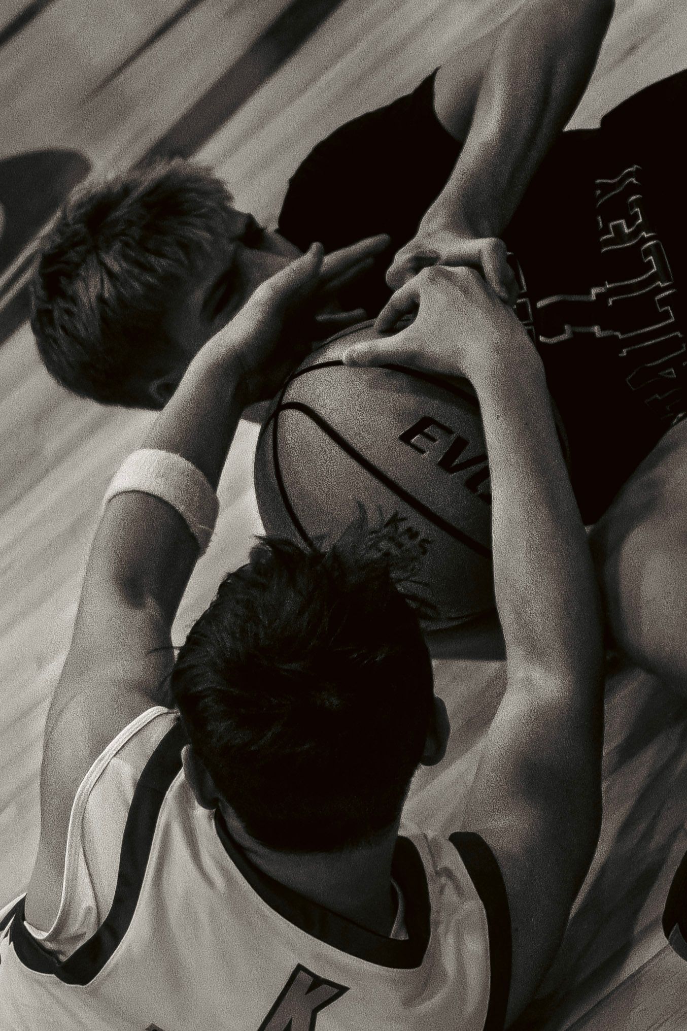 Black and white overhead view of two basketball players battling for possession of the ball.