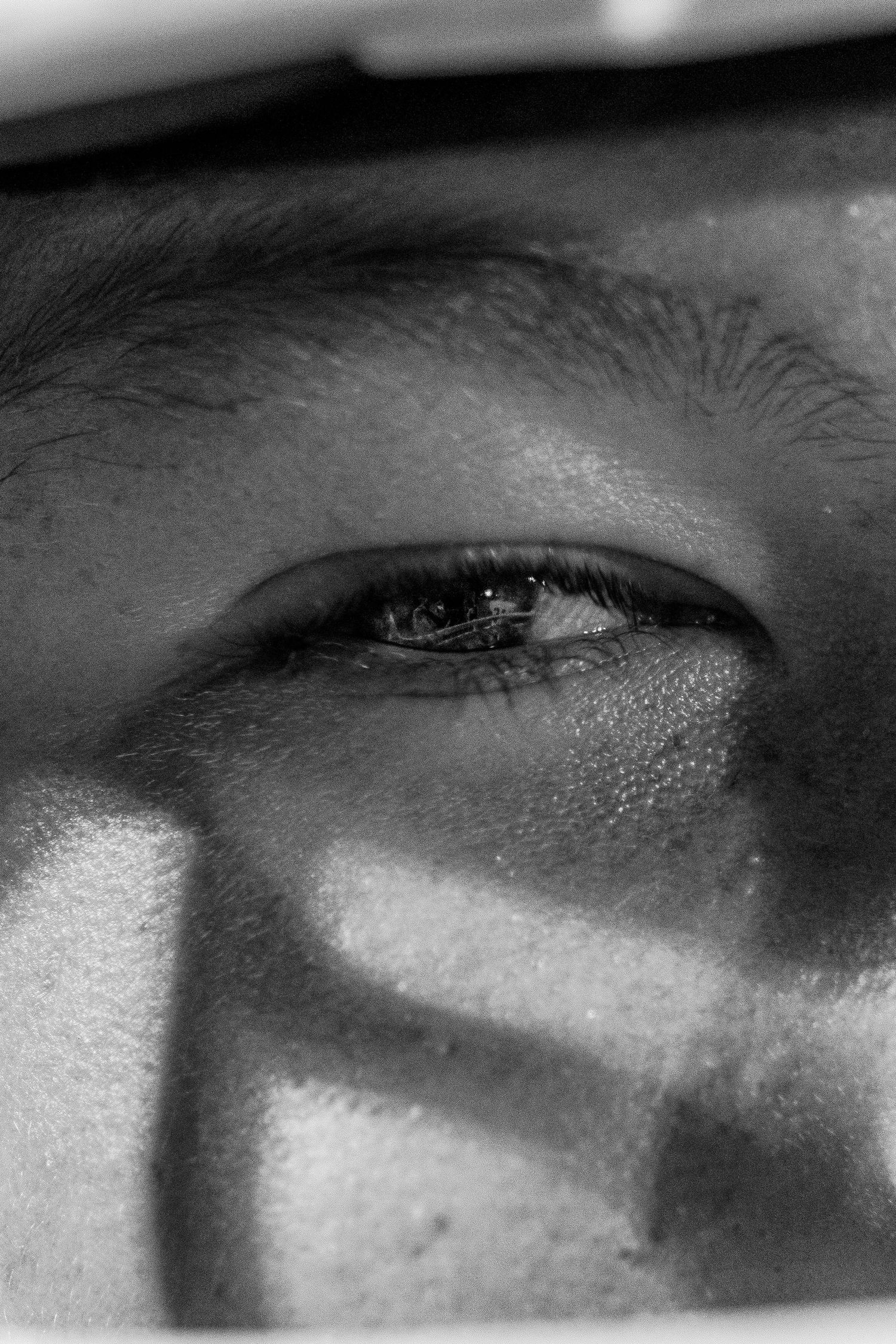 Dramatic black and white extreme close-up of a football player's eye through a helmet.