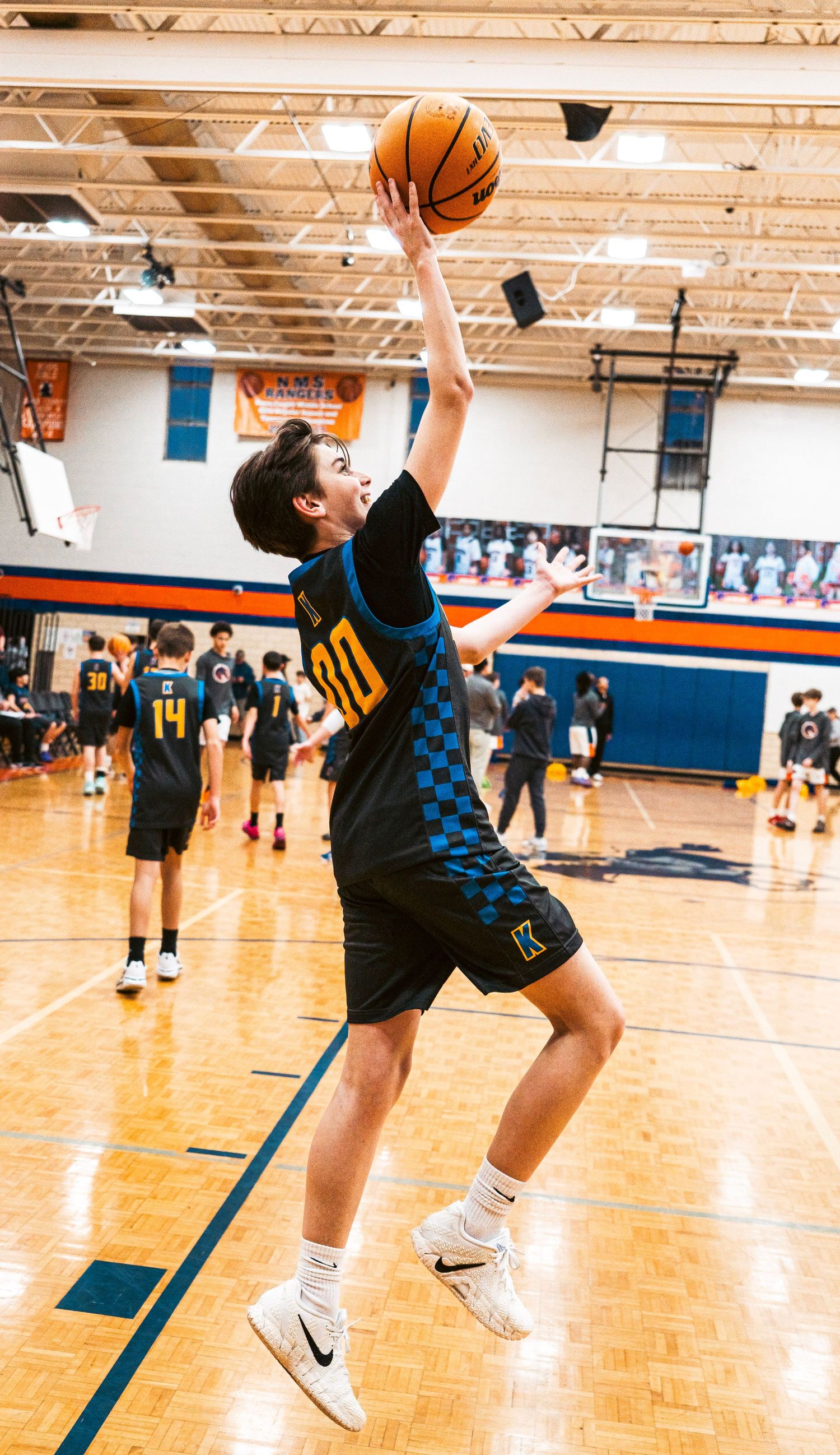 Young basketball player number 30 practices jump shot in school gymnasium.