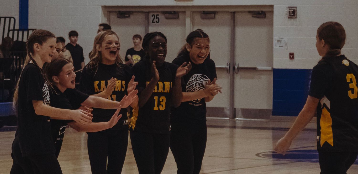 Karns basketball players celebrate together on the court in black and gold uniforms.