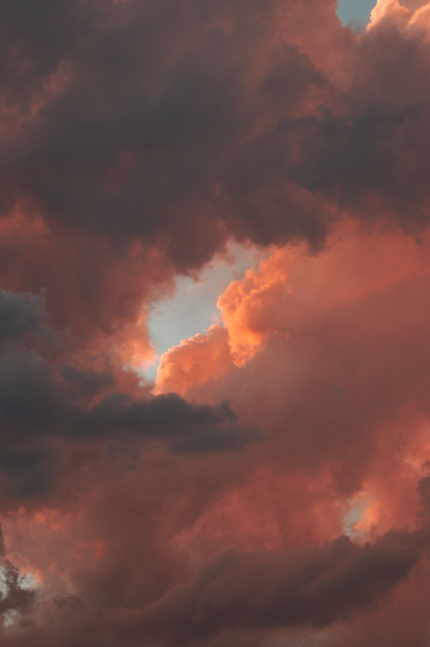 Dramatic sunset sky with glowing orange and pink clouds parting to reveal a bright patch of light.