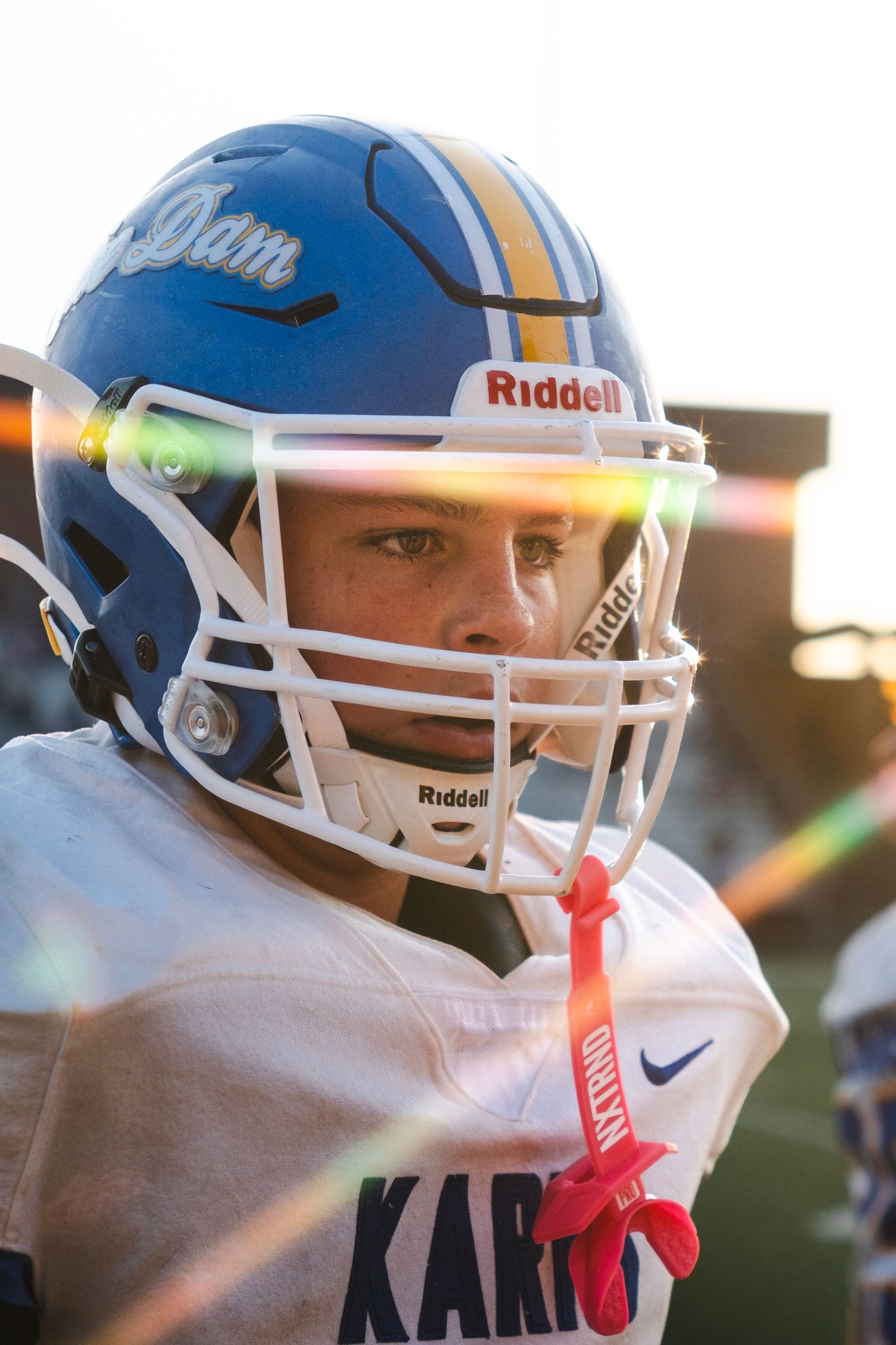 Close-up of a football player wearing a blue Riddell helmet with face mask during a game.