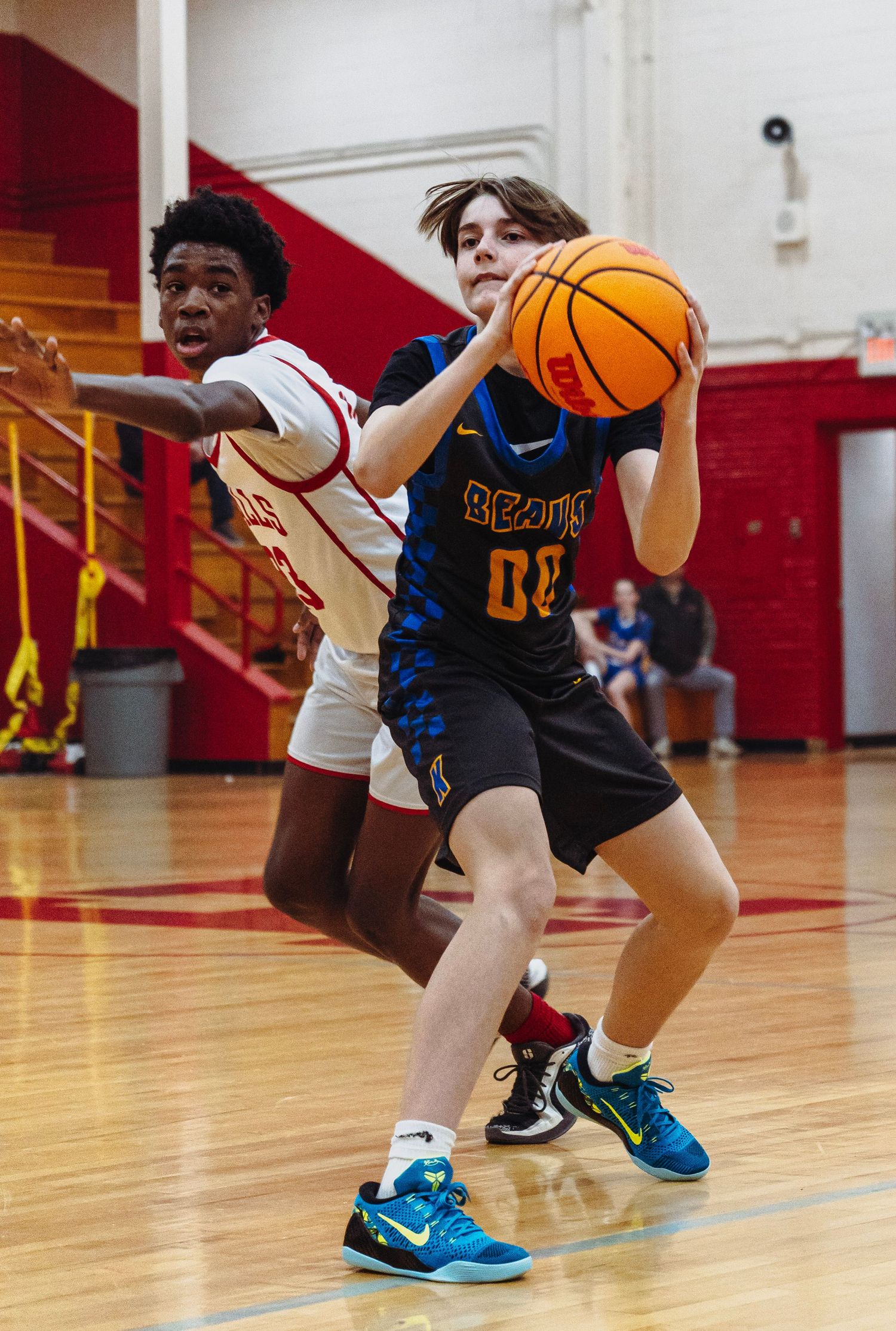 A basketball player in a Beav jersey drives past a defender during an indoor high school game.