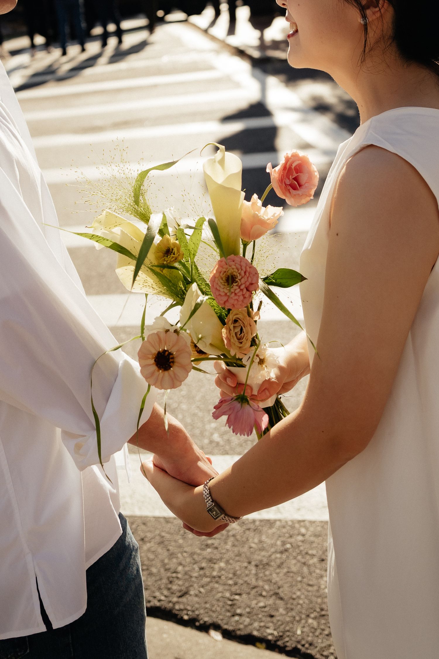 A close-up of hands holding a romantic bouquet featuring pink and white blooms.