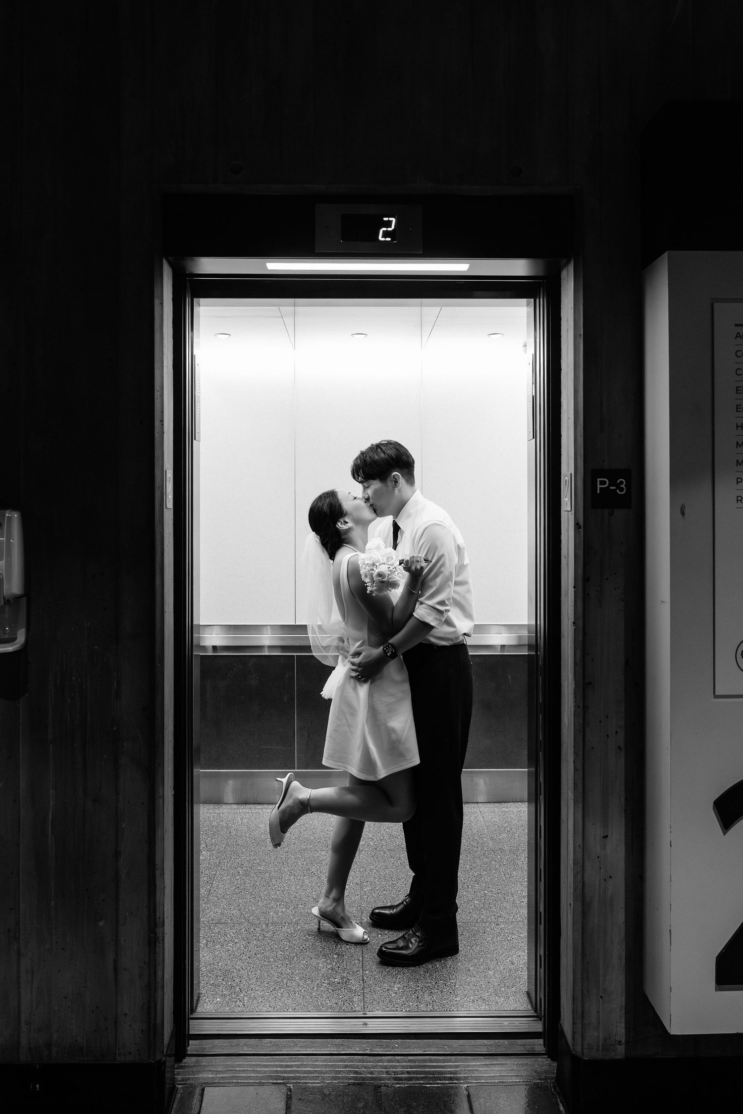 Black and white photo of a romantic moment in an elevator showing number 2.