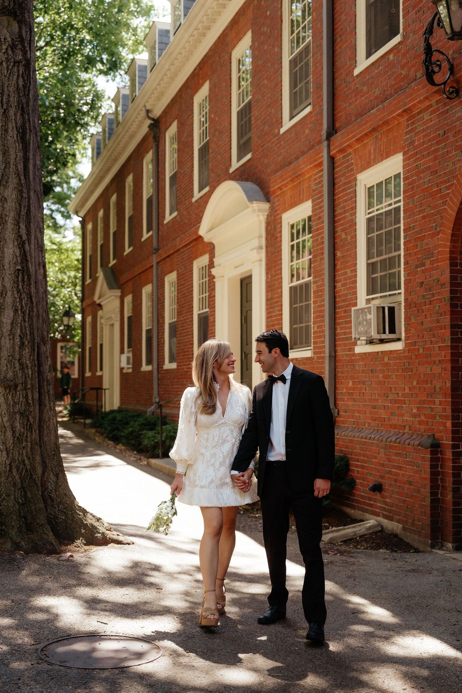 Sunlit brick walkway creates perfect backdrop for elegant couple's portrait.