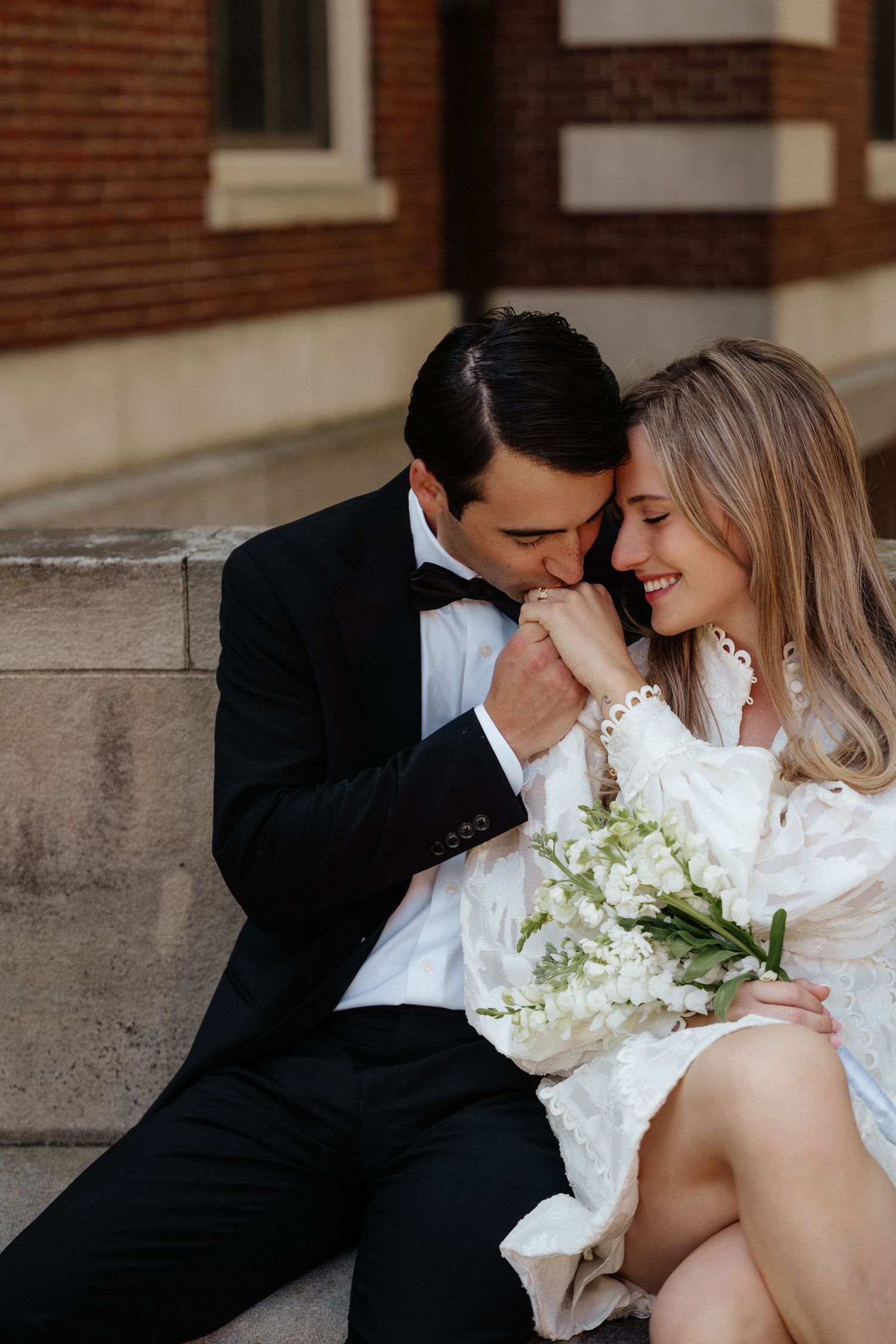Romantic moment shared on stone steps with white dress and classic black tuxedo.