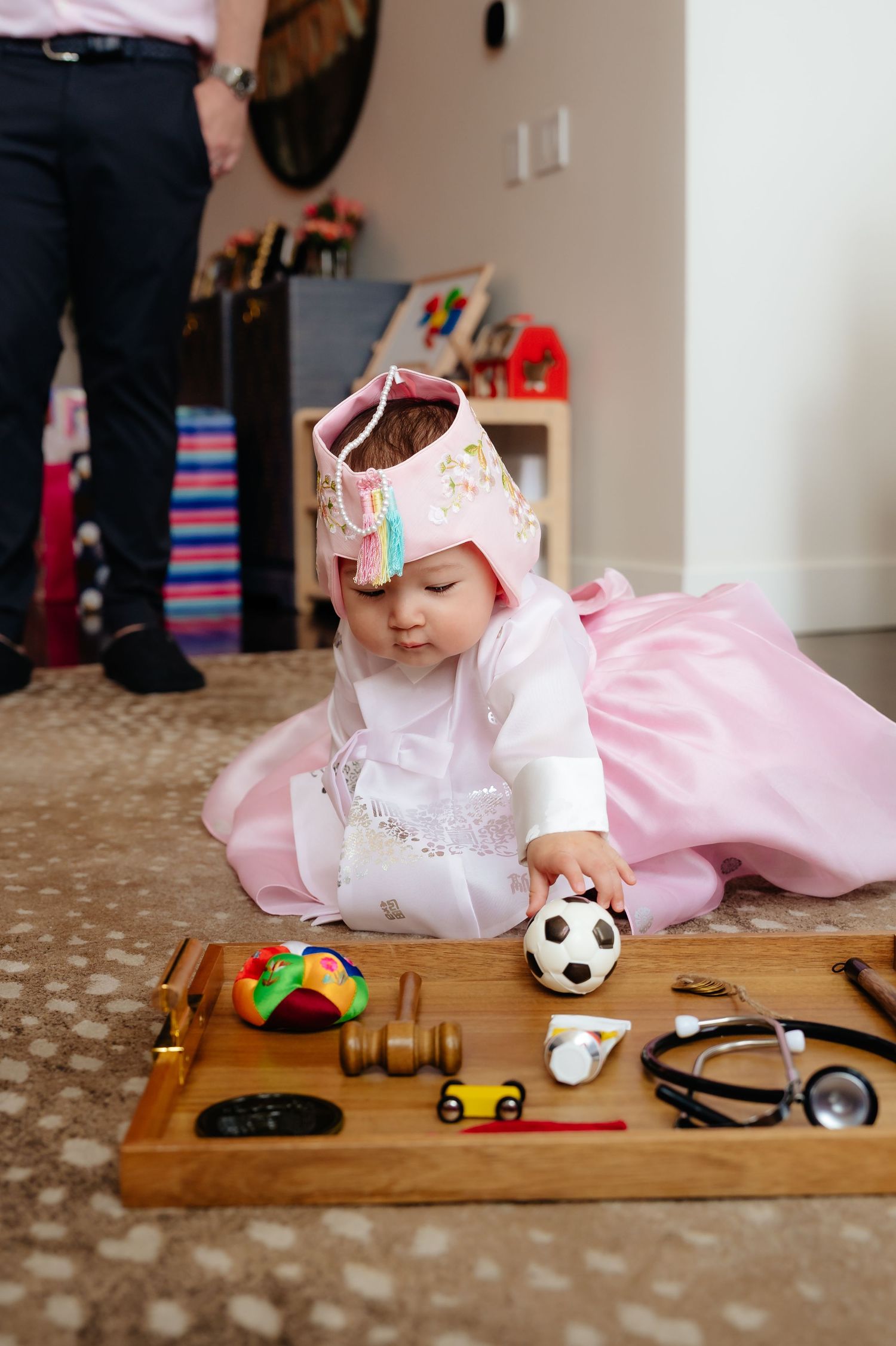 Pink-dressed figure playing with various toys on a wooden board.