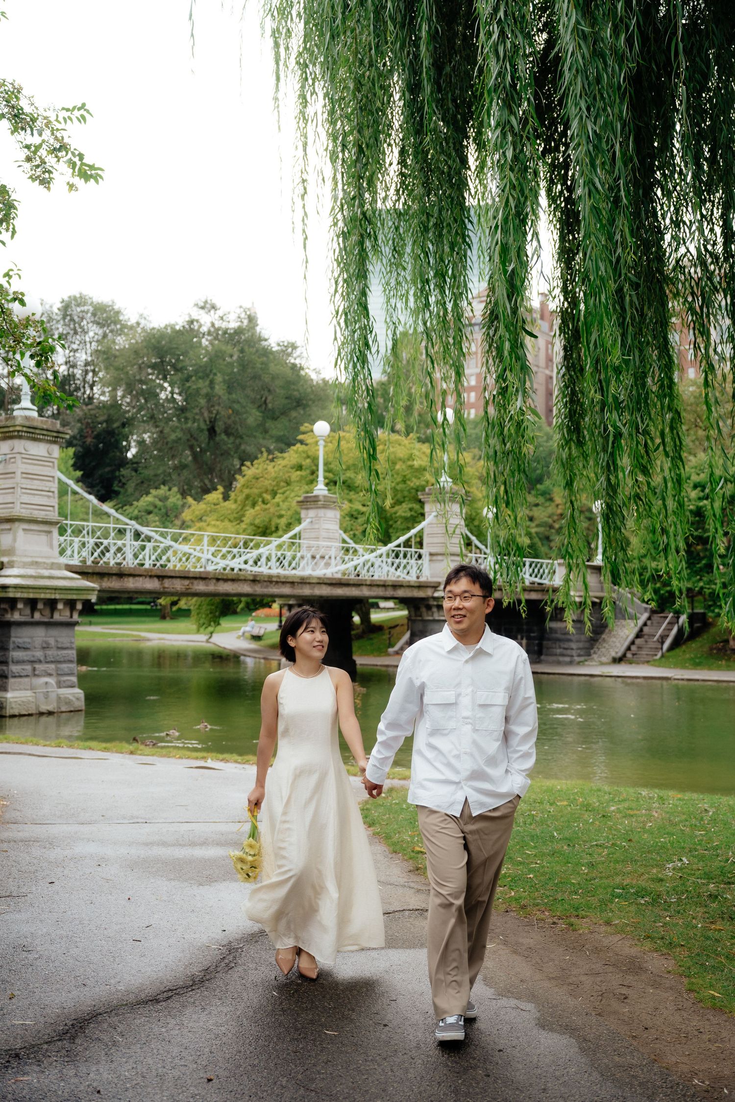 Boston Public Garden engagement photo with the couple near a willow tree and Swan Boat pond.