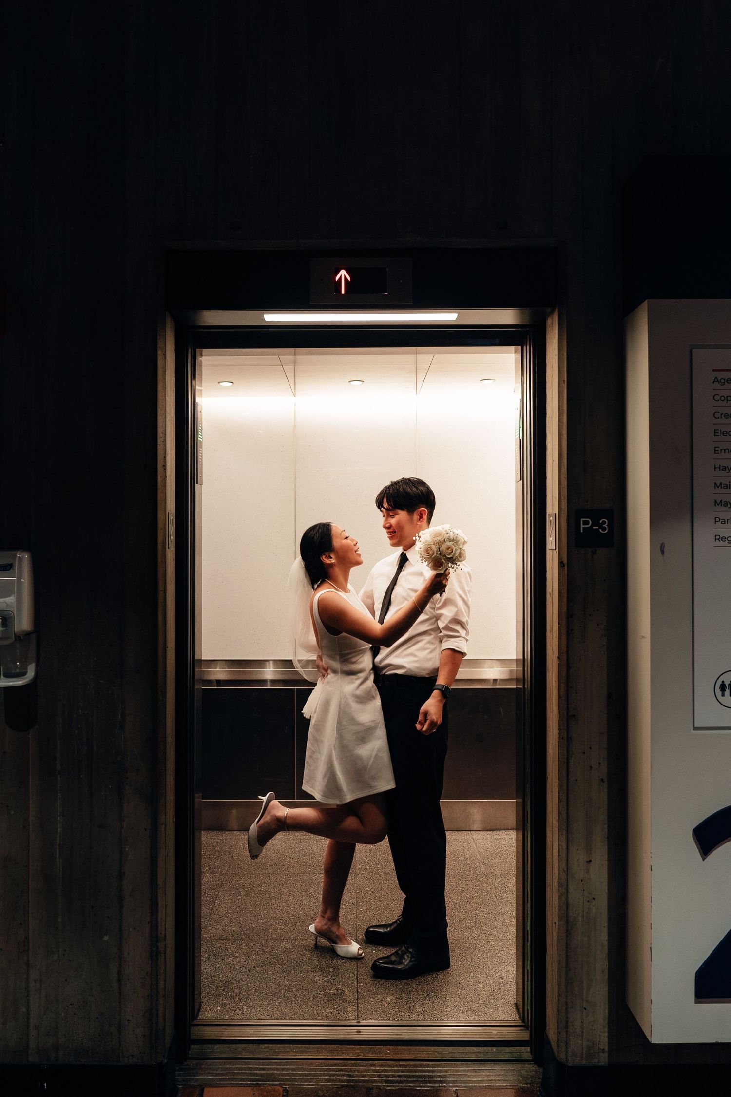 A romantic couple moment captured in a brightly lit elevator.