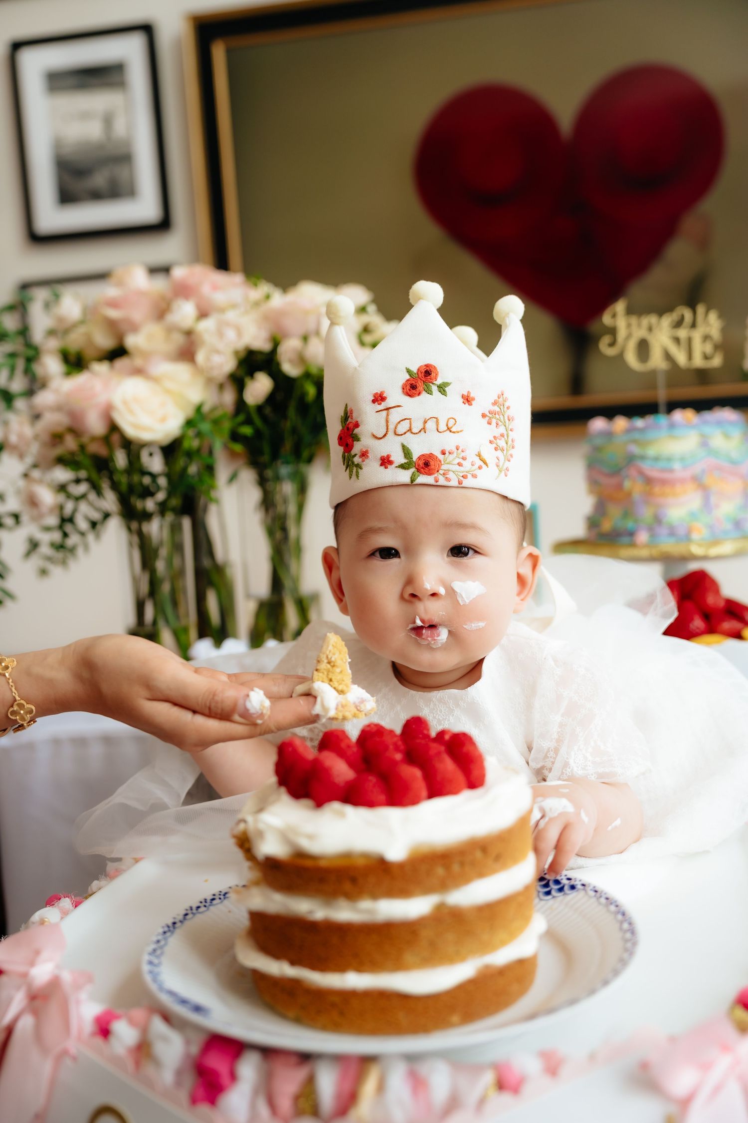 First birthday celebration with a layered cake and decorative crown.