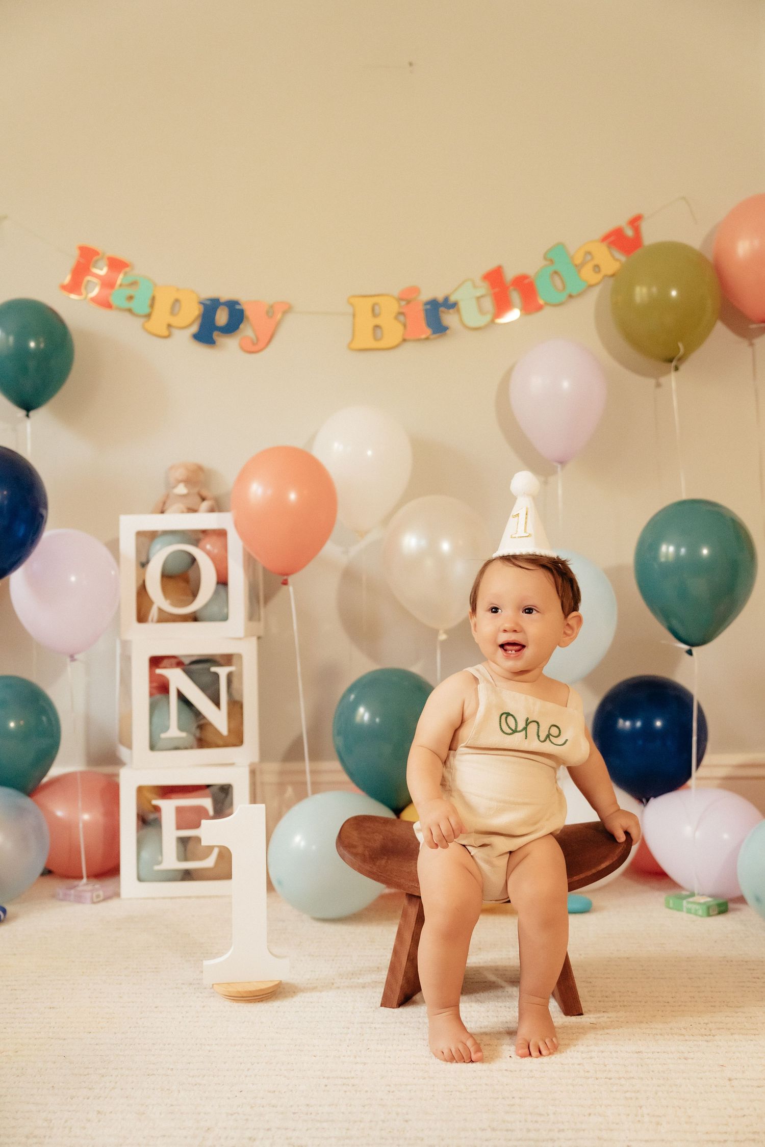 Colorful birthday party setup with balloons and decorative letters against a light background.
