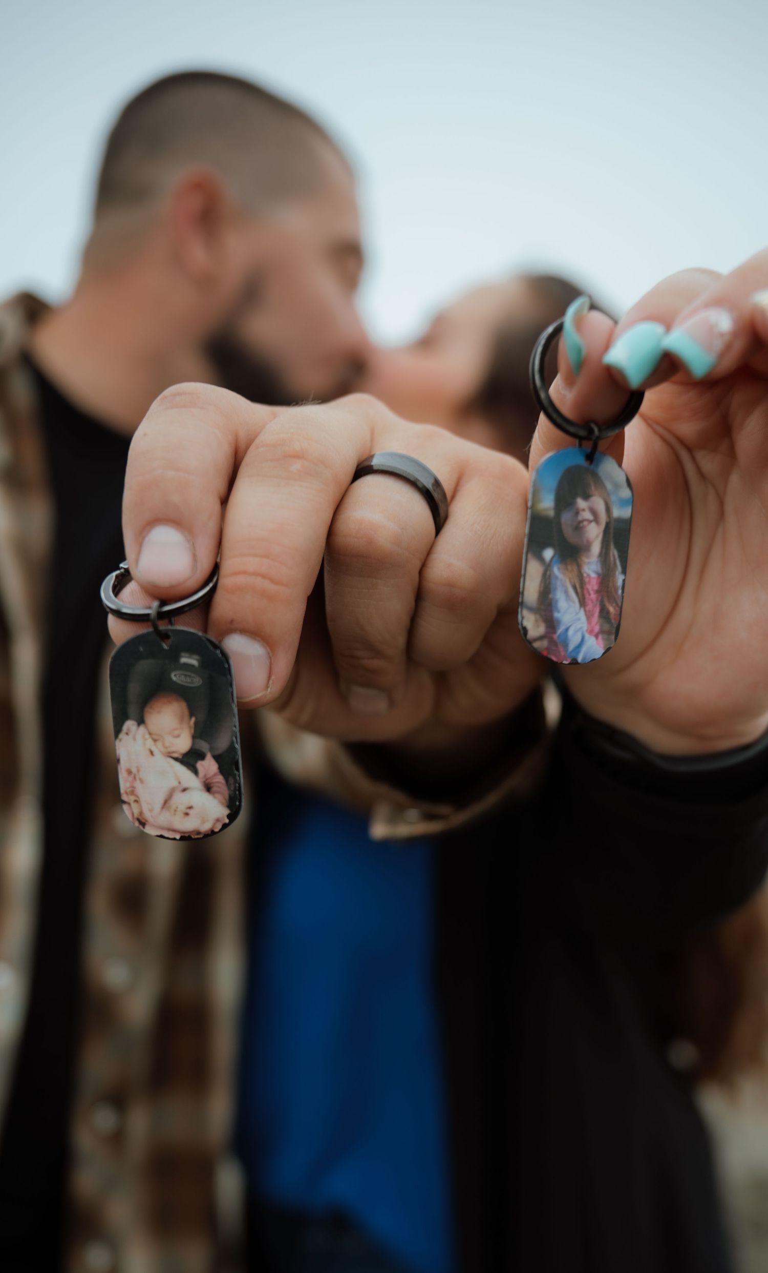 Close-up of hands displaying multiple photo keychains in a row.