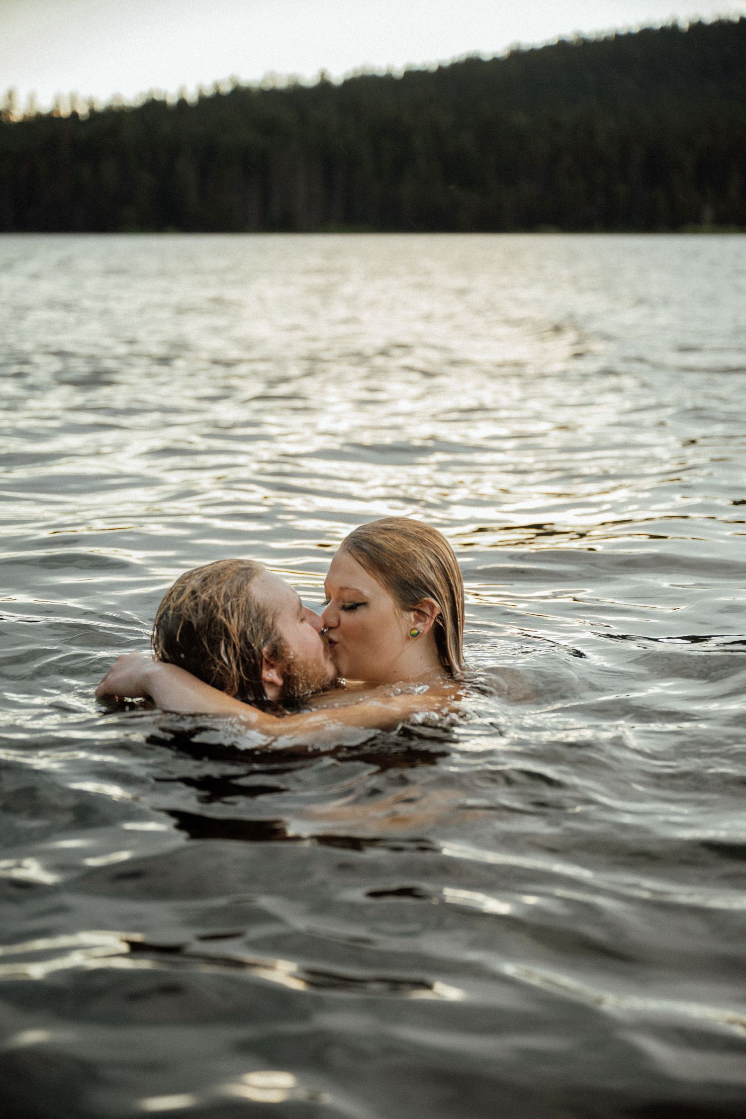 Couple sharing an intimate moment while floating in a mountain lake.