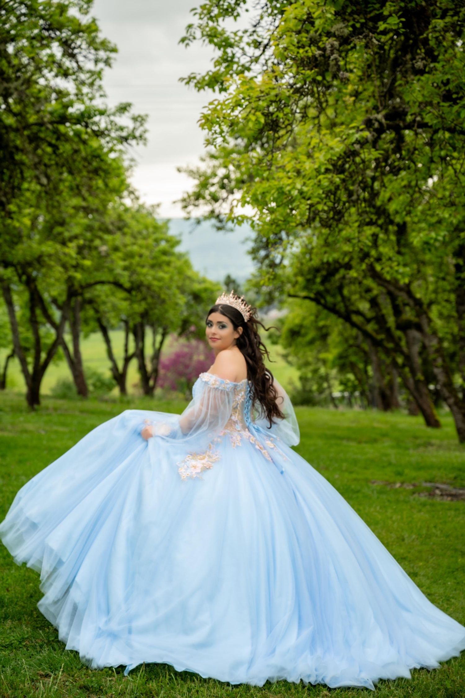 A powder blue princess ballgown with full skirt captured in a scenic orchard landscape.