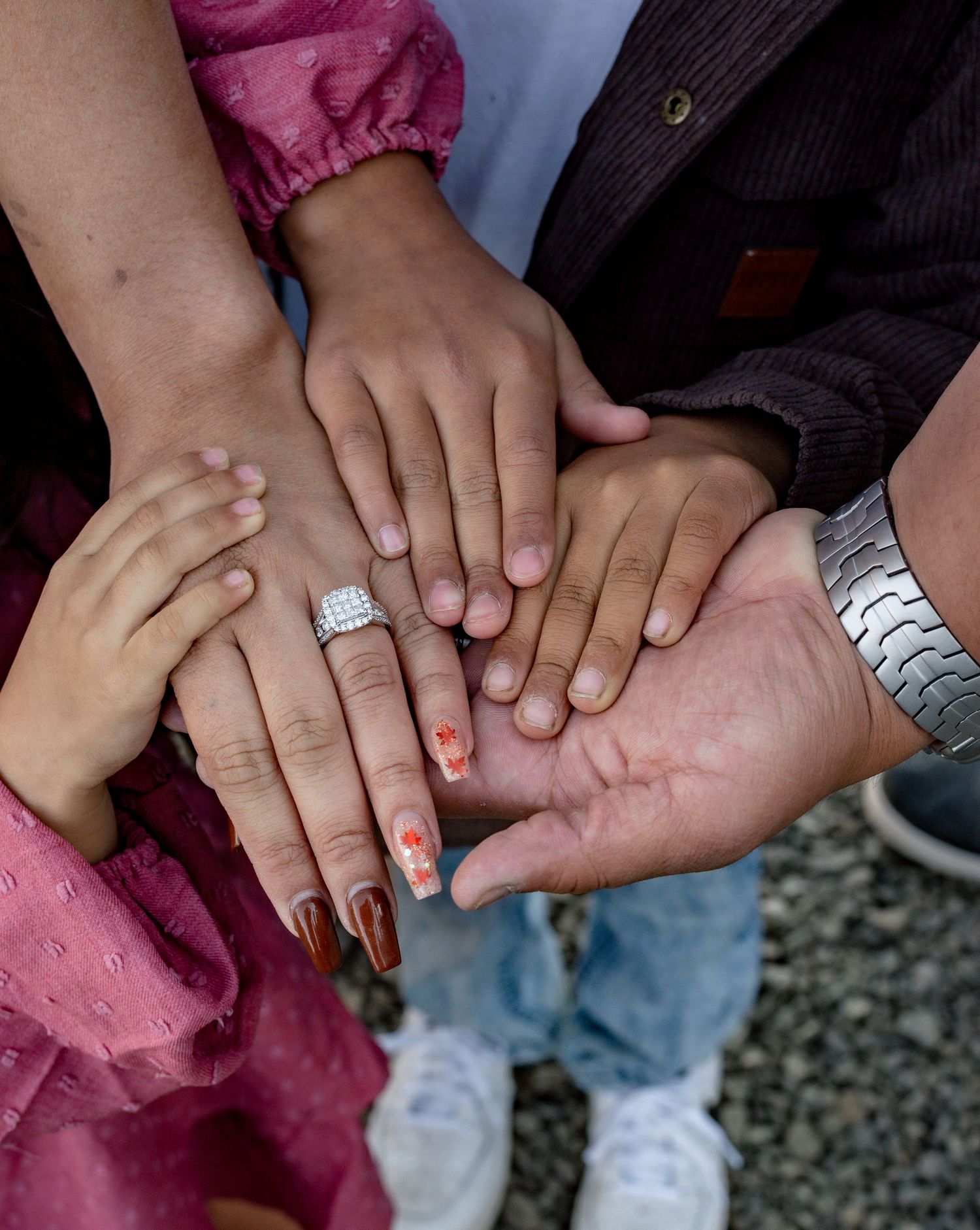 Close-up of hands holding and touching in a tender moment on a gravel path.