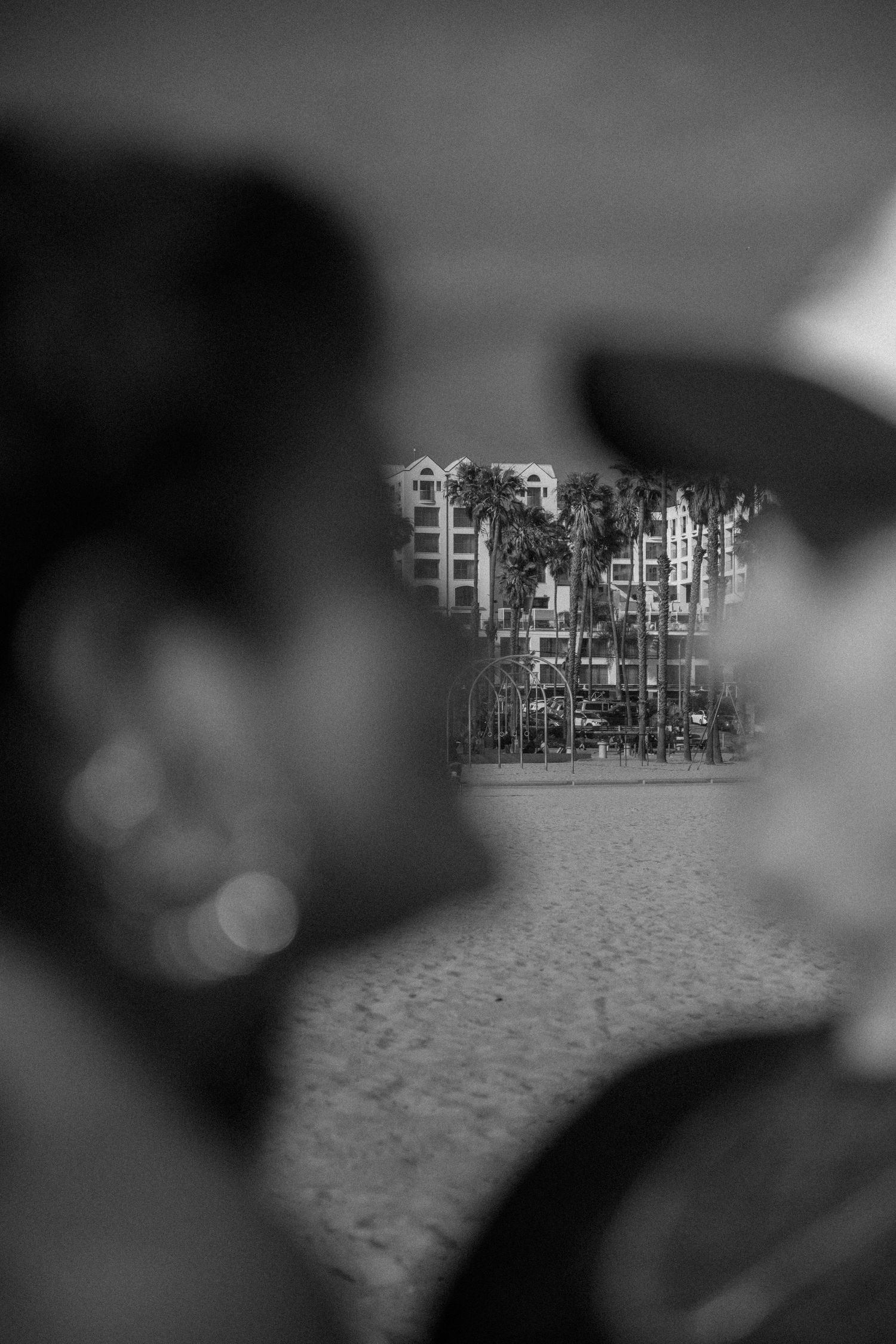 A black and white photo showing a blurred foreground with amusement park buildings visible in the background.