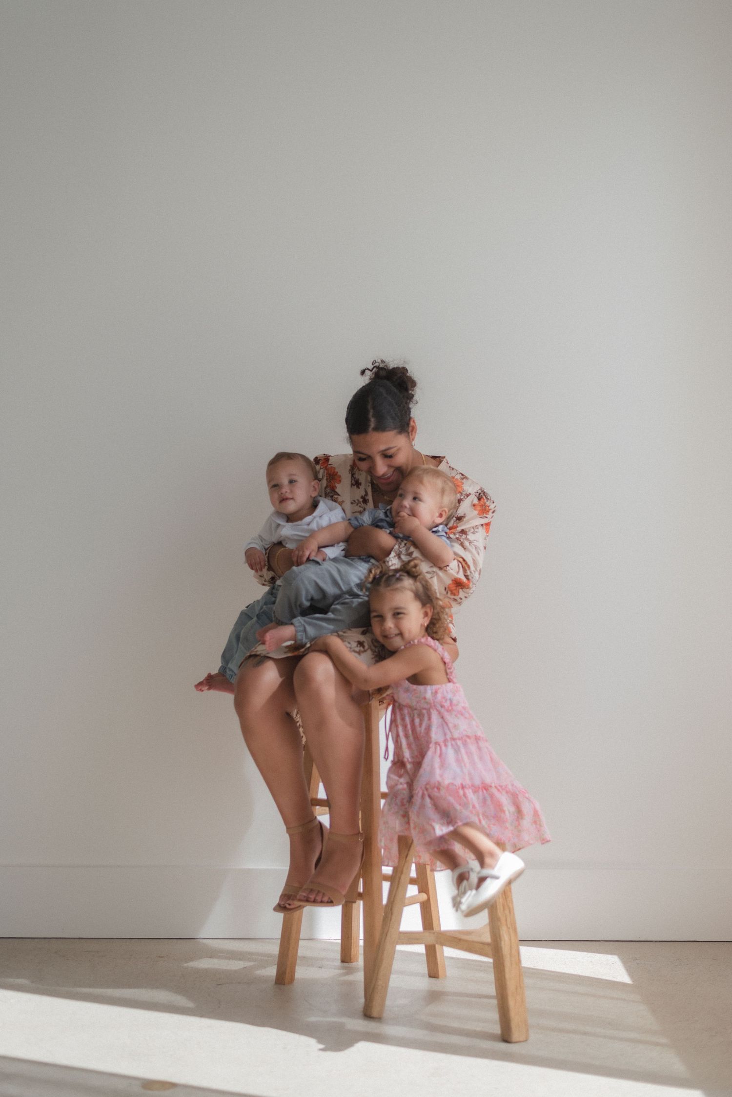 Series of tender moments between caregiver and children on wooden chair against white wall.