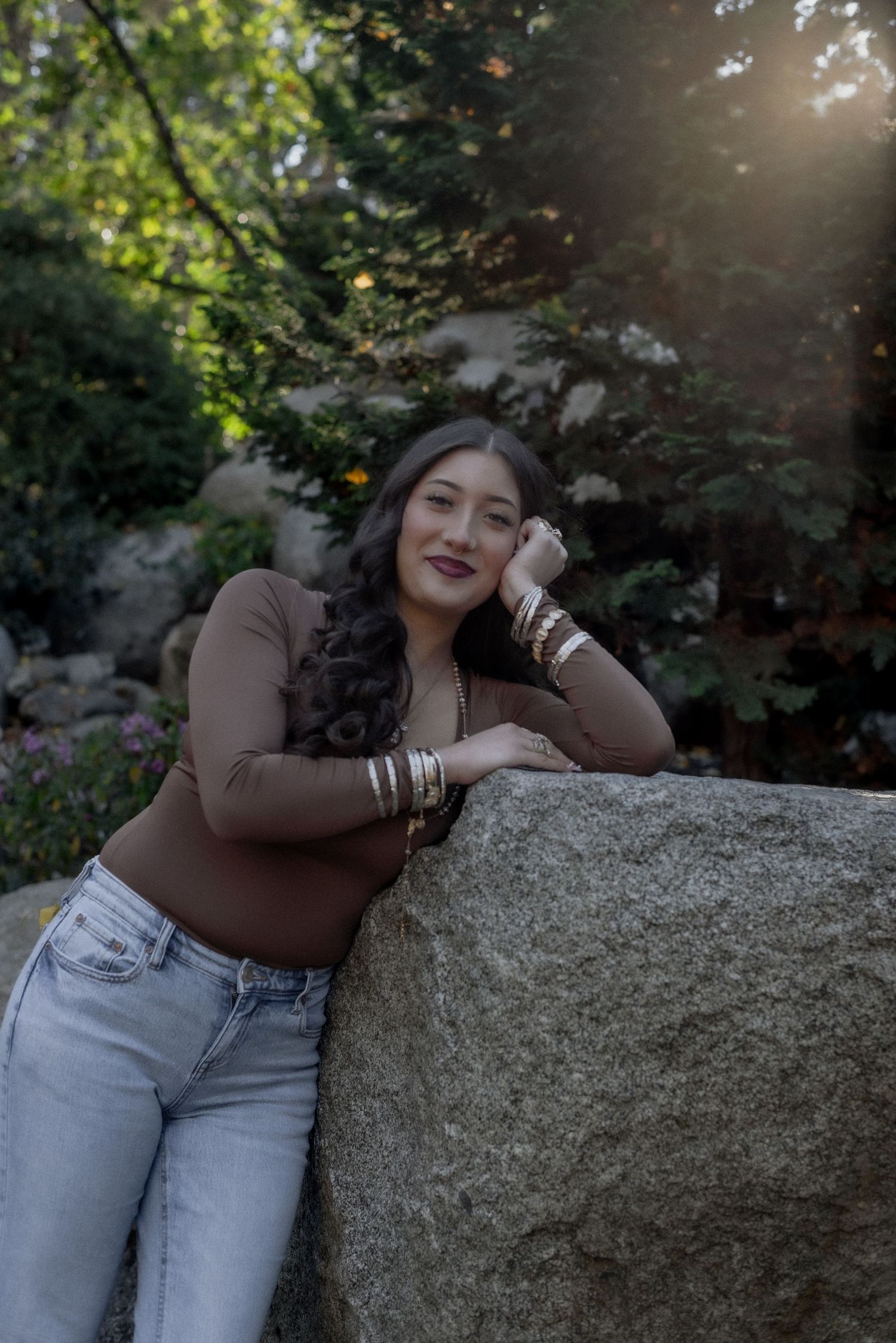 Relaxed poses on stone surface with autumn trees and natural lighting in background.