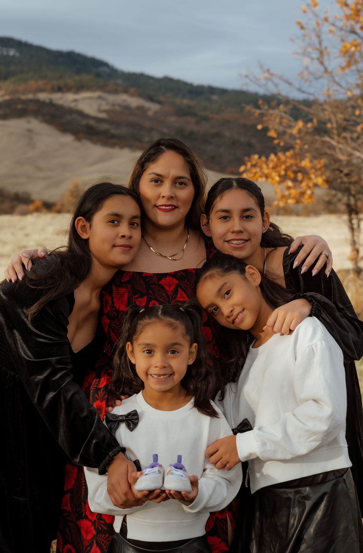 A group portrait taken outdoors against a mountainous autumn landscape.