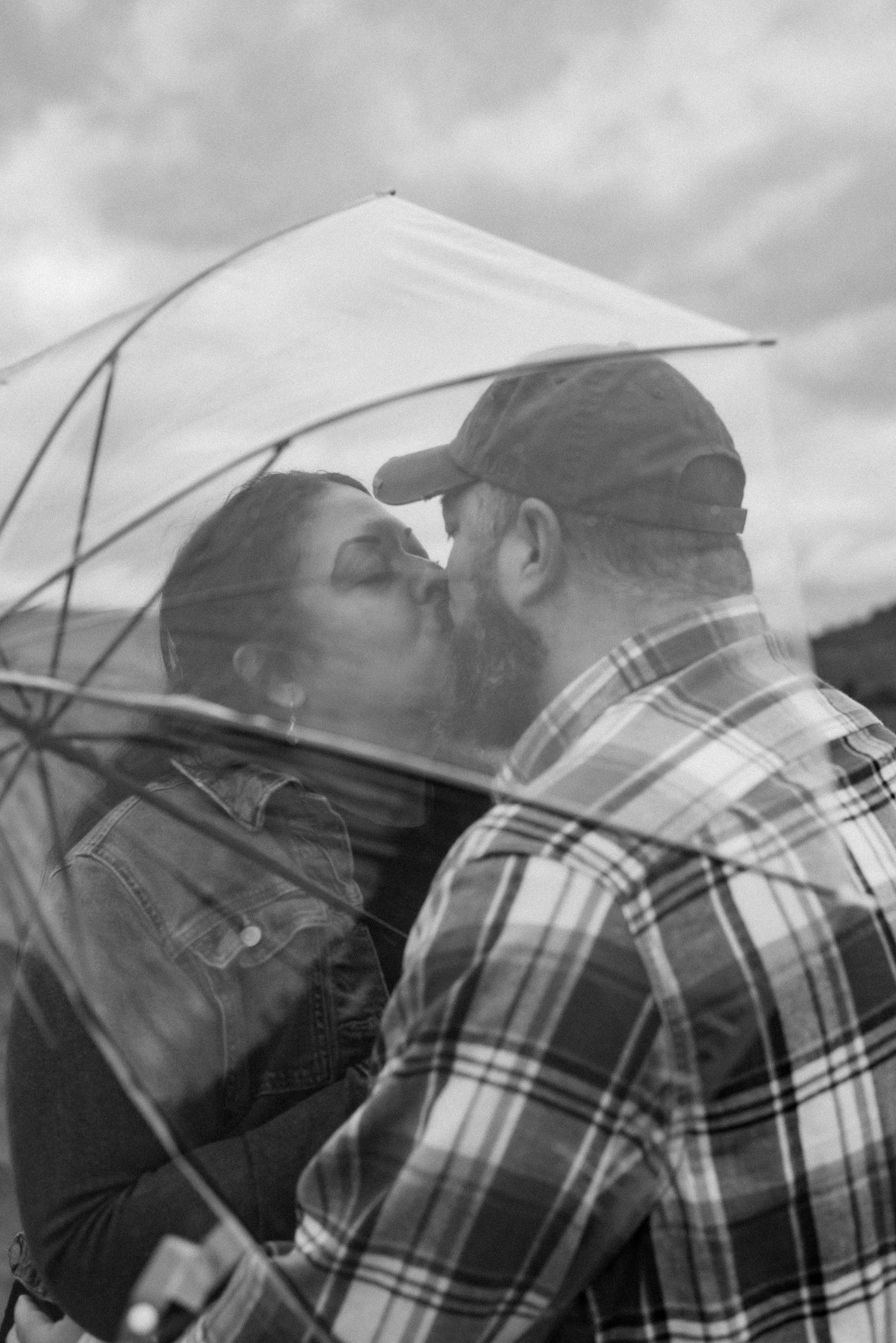 A romantic silhouette of a couple against cloudy skies wearing plaid and casual attire.