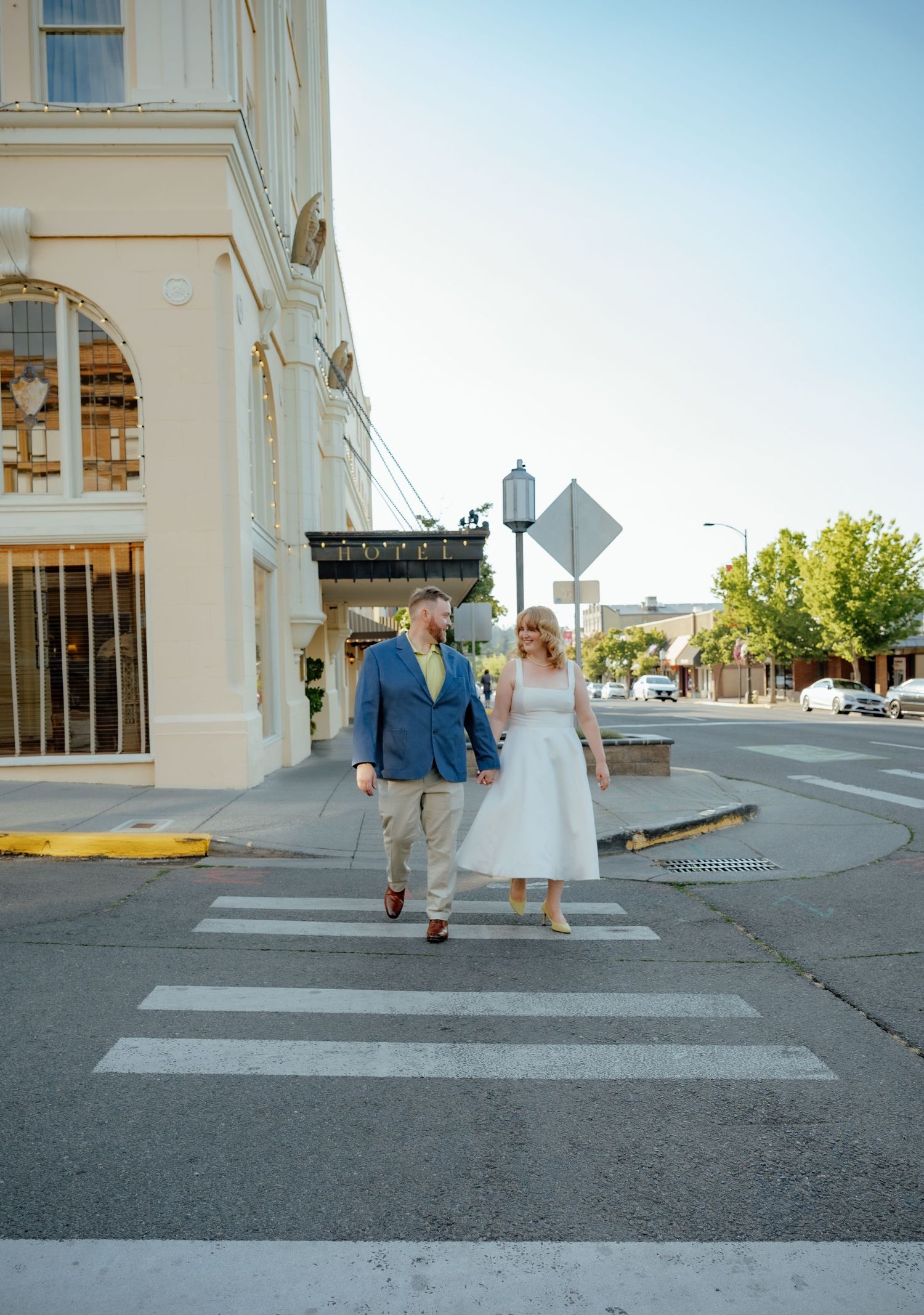 Couple walking across crosswalk in front of historic building.