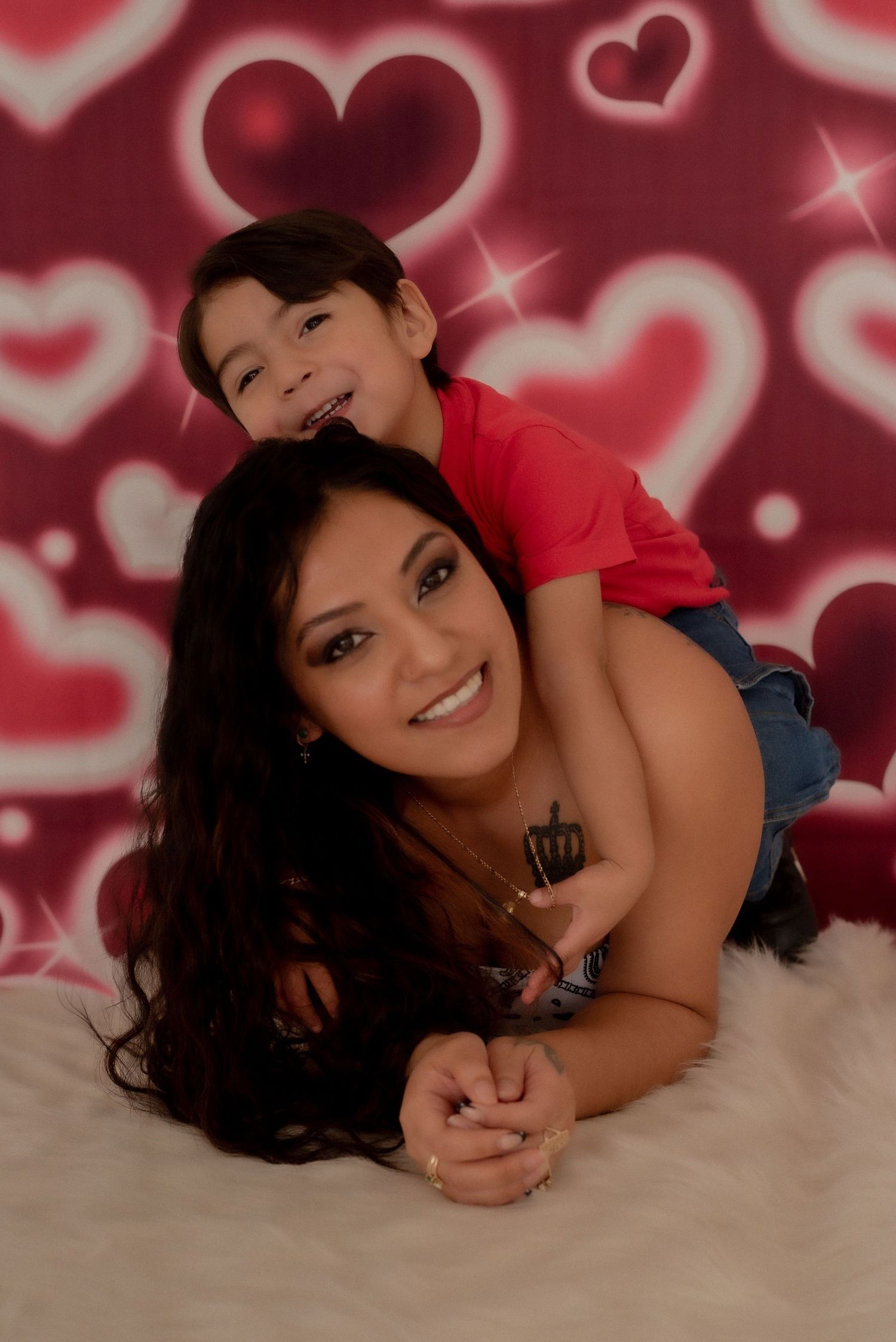 Mother and child sharing sweet moments against romantic heart-patterned backdrop.