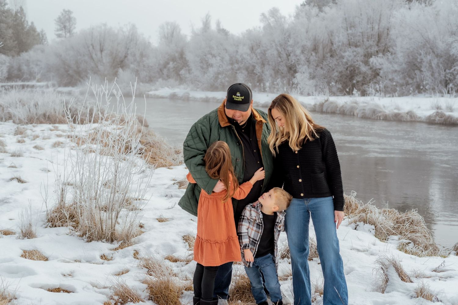 Family enjoys a winter day together in the snow near a frozen river.