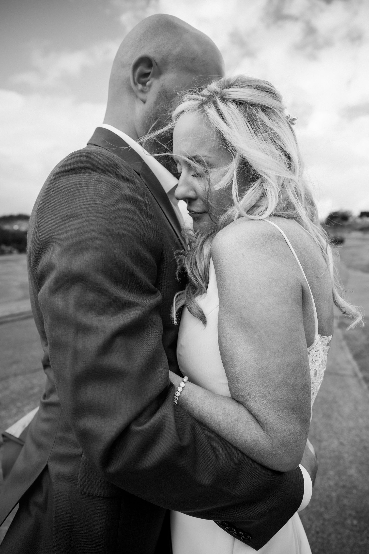 An intimate black and white portrait of a couple sharing a tender moment in formal attire.